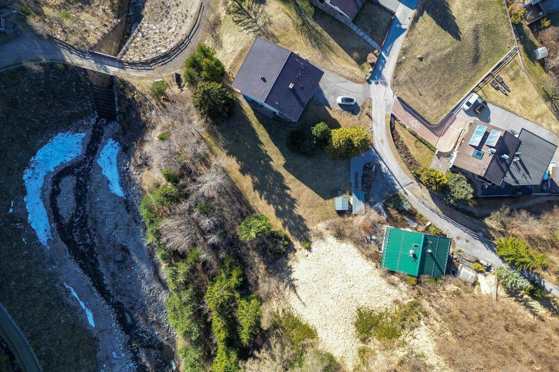 Luftaufnahme des Grundstücks mit Wohnhaus, Wald und Bachlauf.