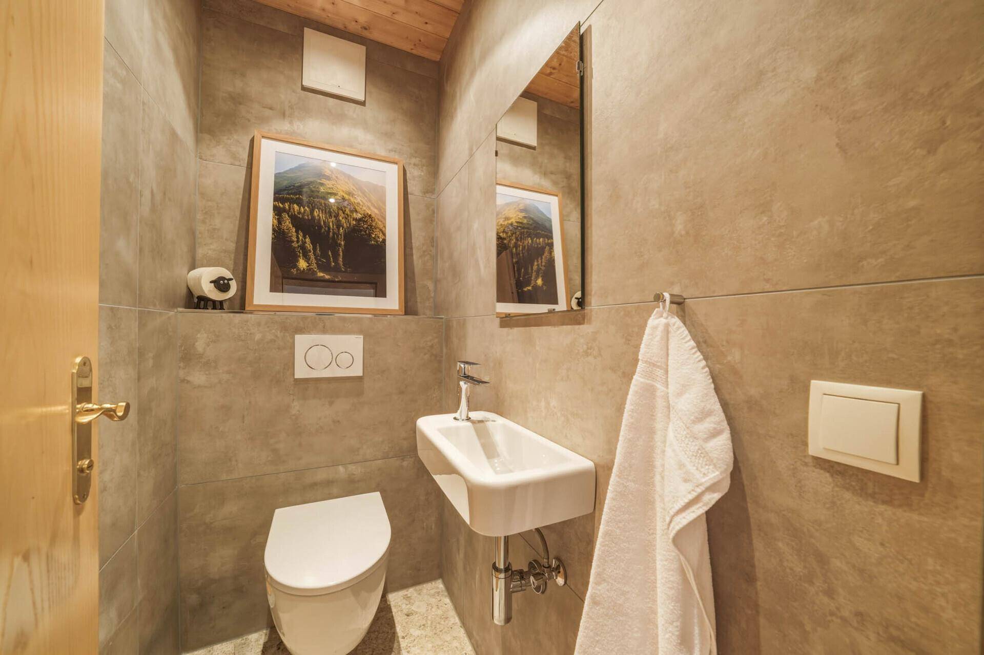 Separate Gästetoilette mit modernen Fliesen, wandhängendem WC und kleinem Waschbecken.