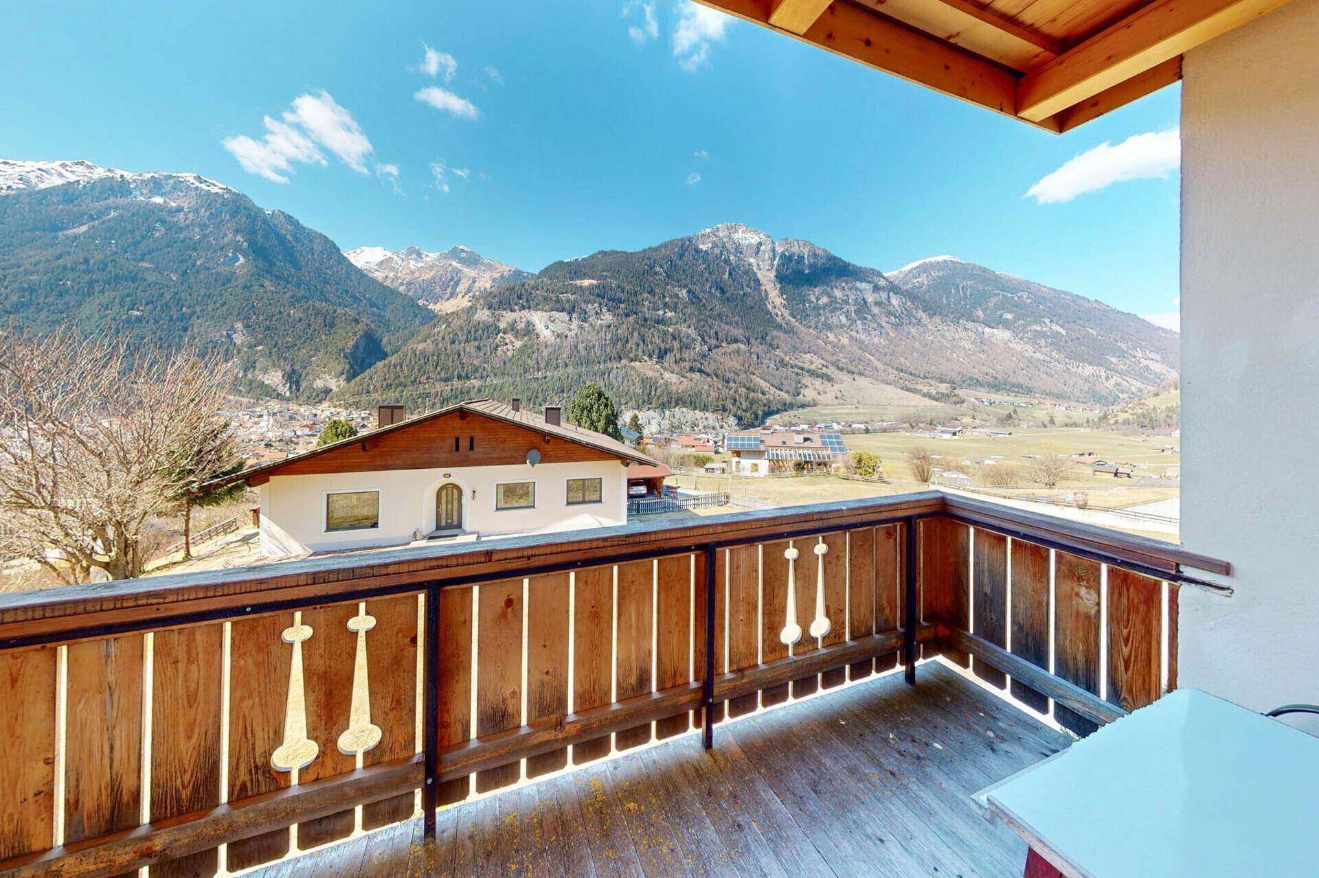 Großer Balkon mit Holzboden und Panoramablick auf die umliegende Berglandschaft.