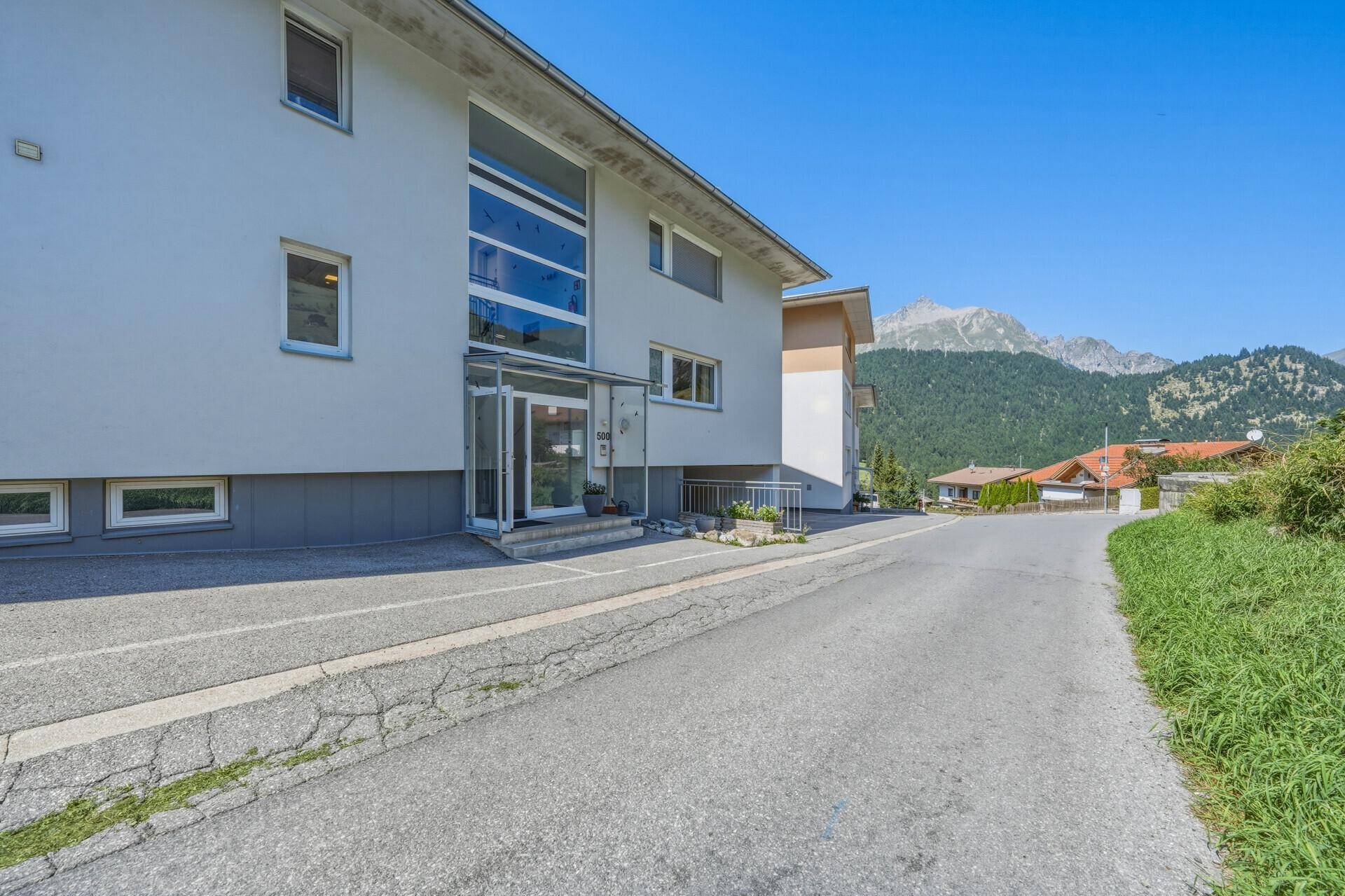 Moderne Gebäudefassade mit großen Fenstern, Balkonen und einem weiten Bergblick.