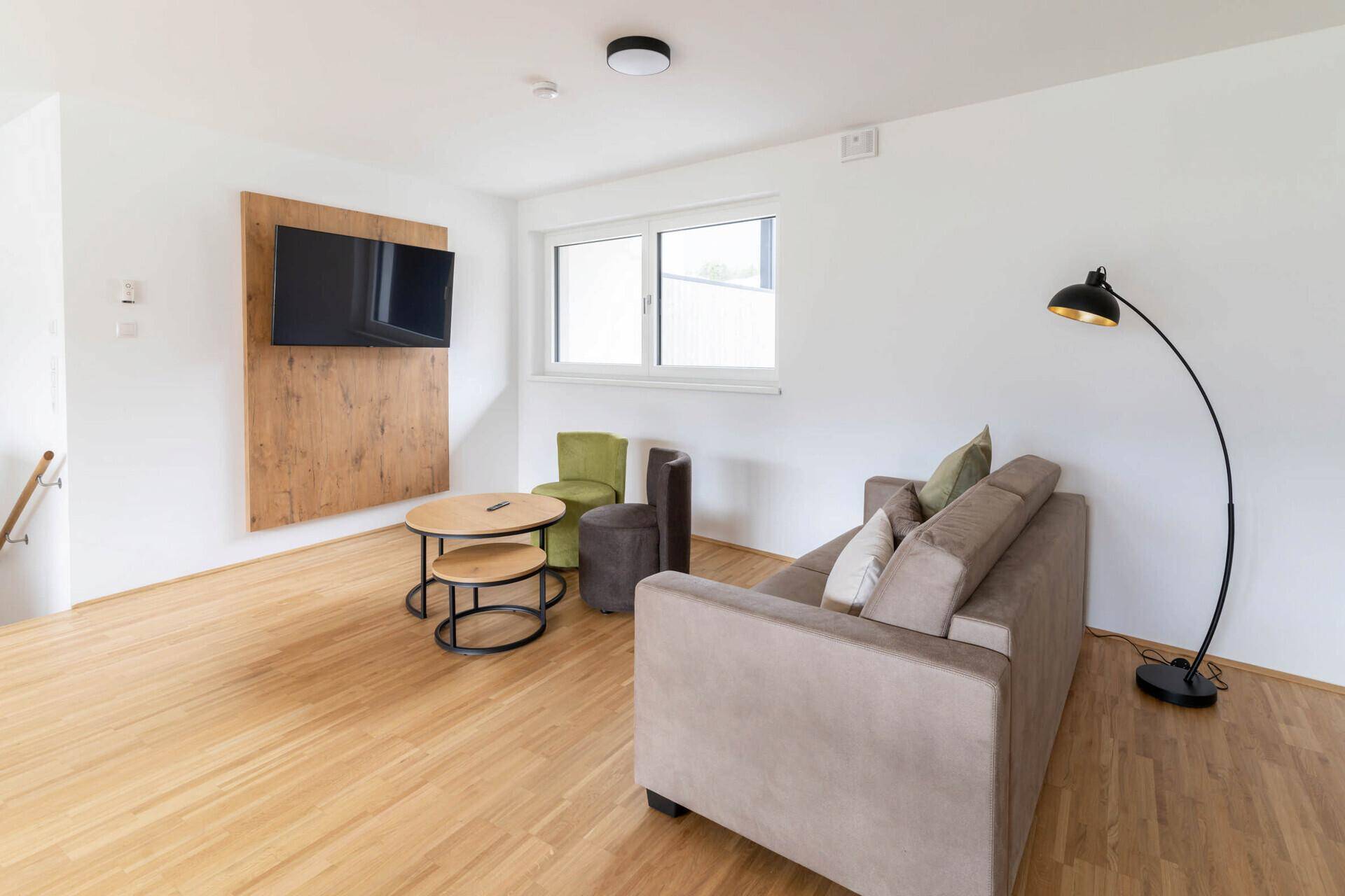 Gemütliches Wohnzimmer mit Sofa, Couchtisch und einem Wandfernseher.