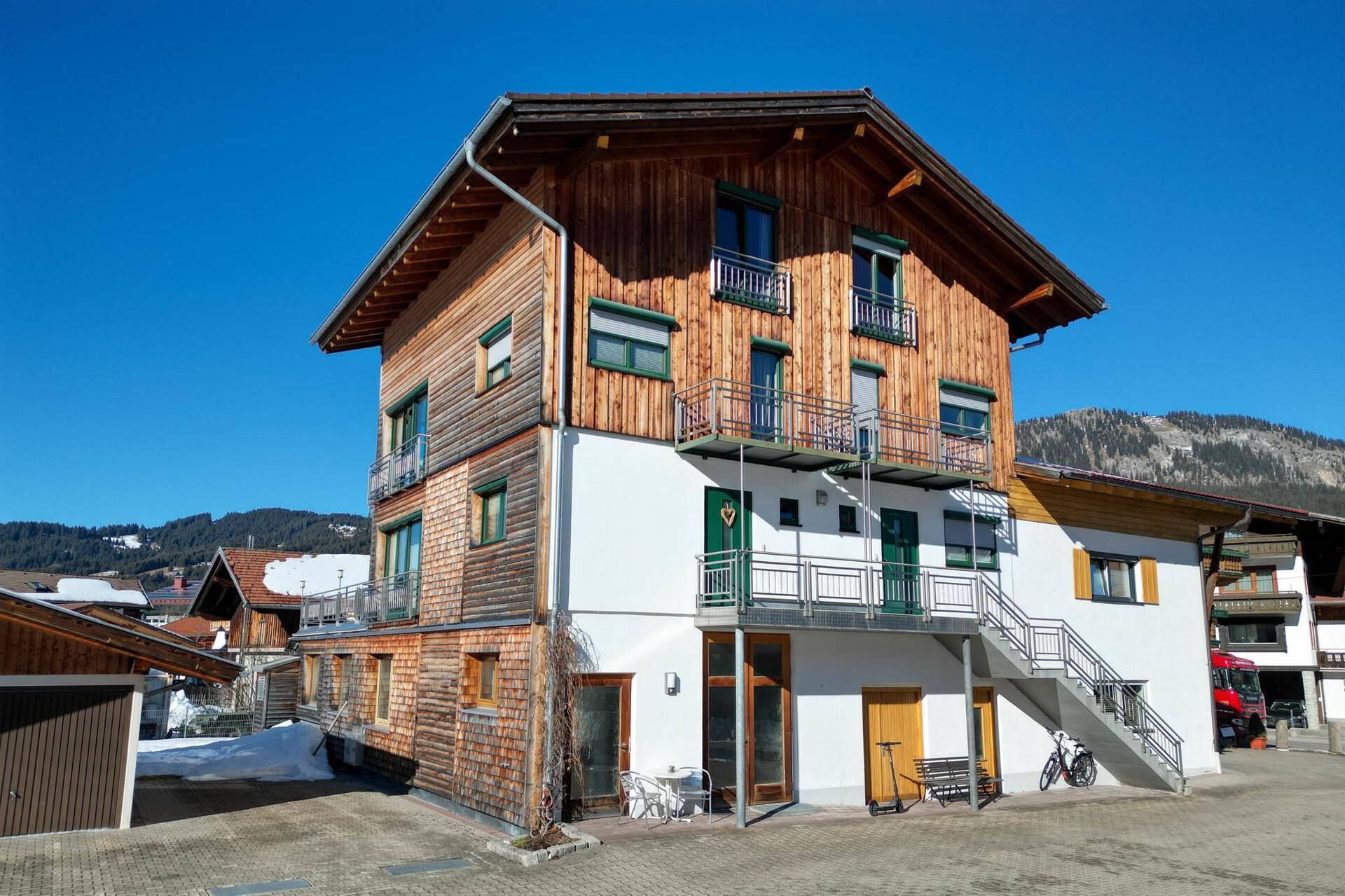 Charmantes Mehrfamilienhaus mit Holzfassade und Balkonen in sonniger Lage.
