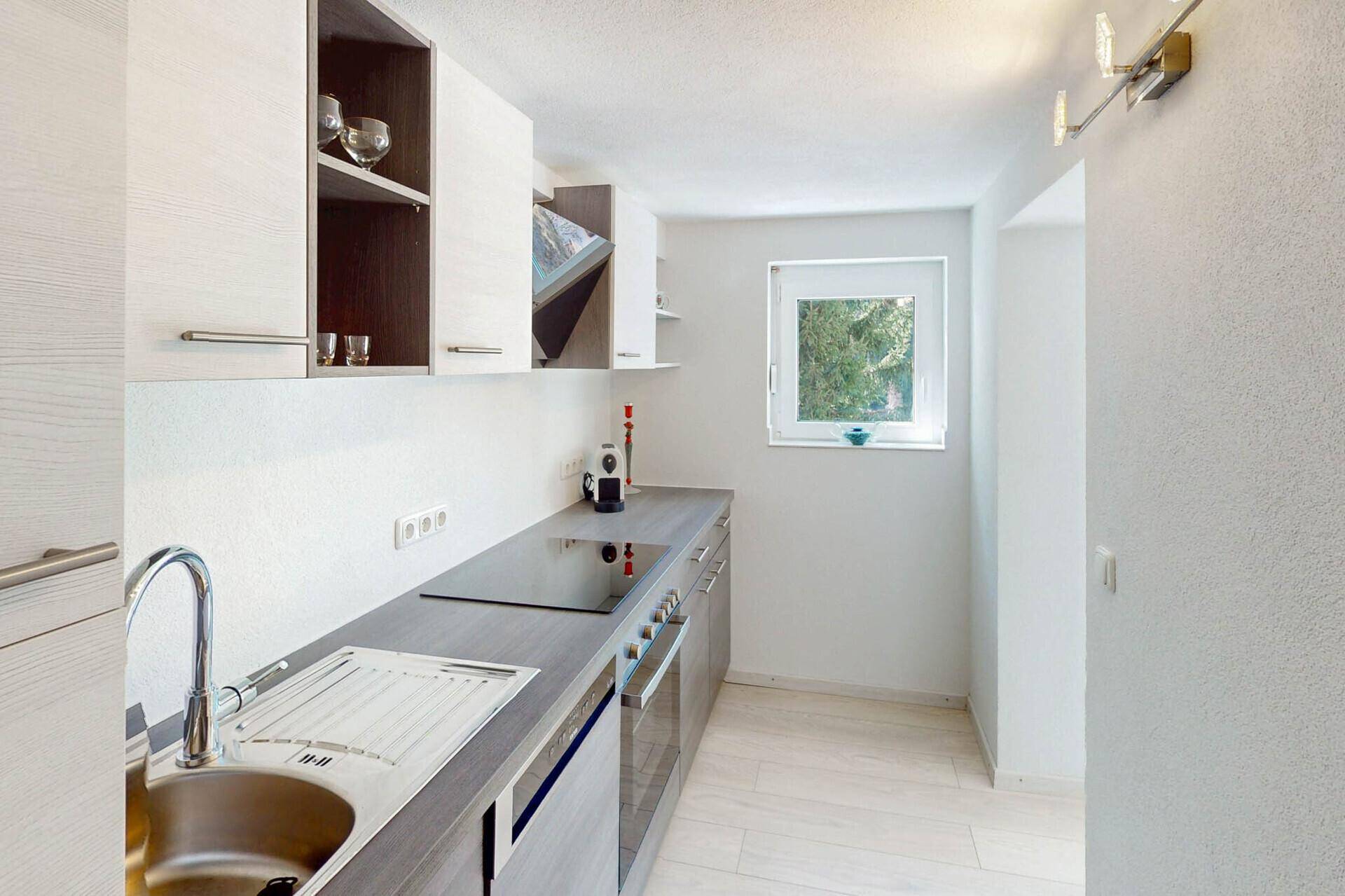 Moderne Küche mit Induktionskochfeld, Holzoptik-Arbeitsplatte und Fenster.