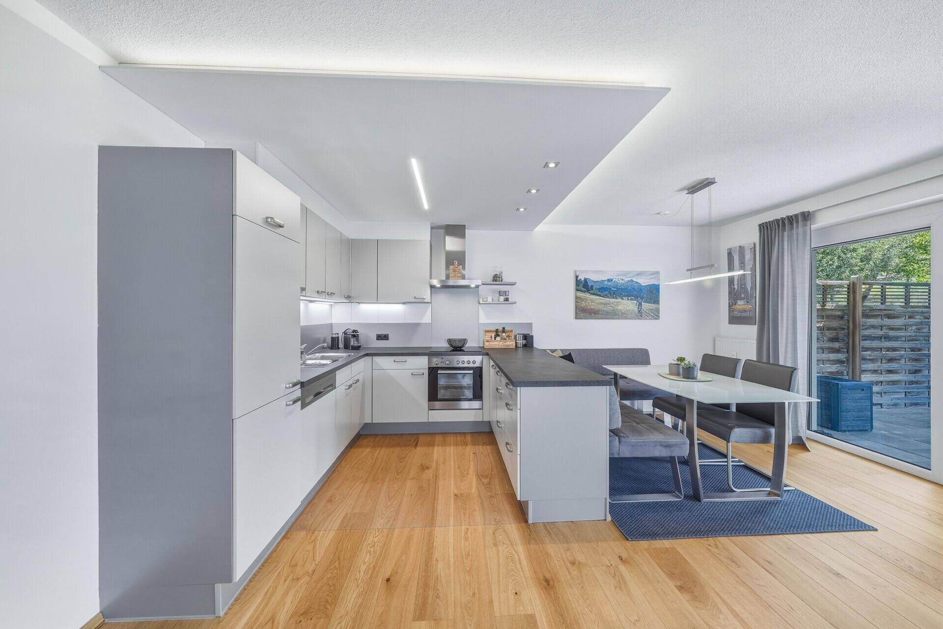 Geräumige moderne Küche mit Essbereich, Holzboden und Ausgang zur Terrasse.