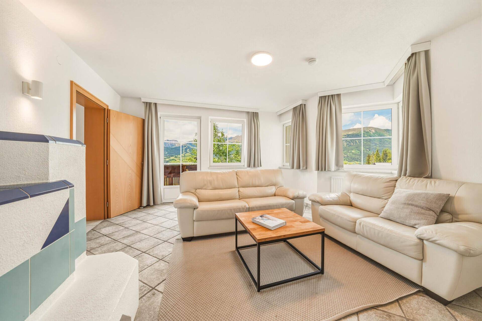 Helles Wohnzimmer mit bequemen Sofas, Bergblick und Zugang zum Balkon.