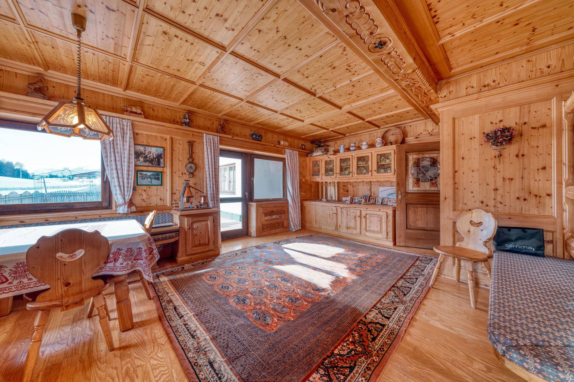 Heller Wohn-Essbereich mit Holzboden, traditionellen Möbeln und Zugang zum Außenbereich.