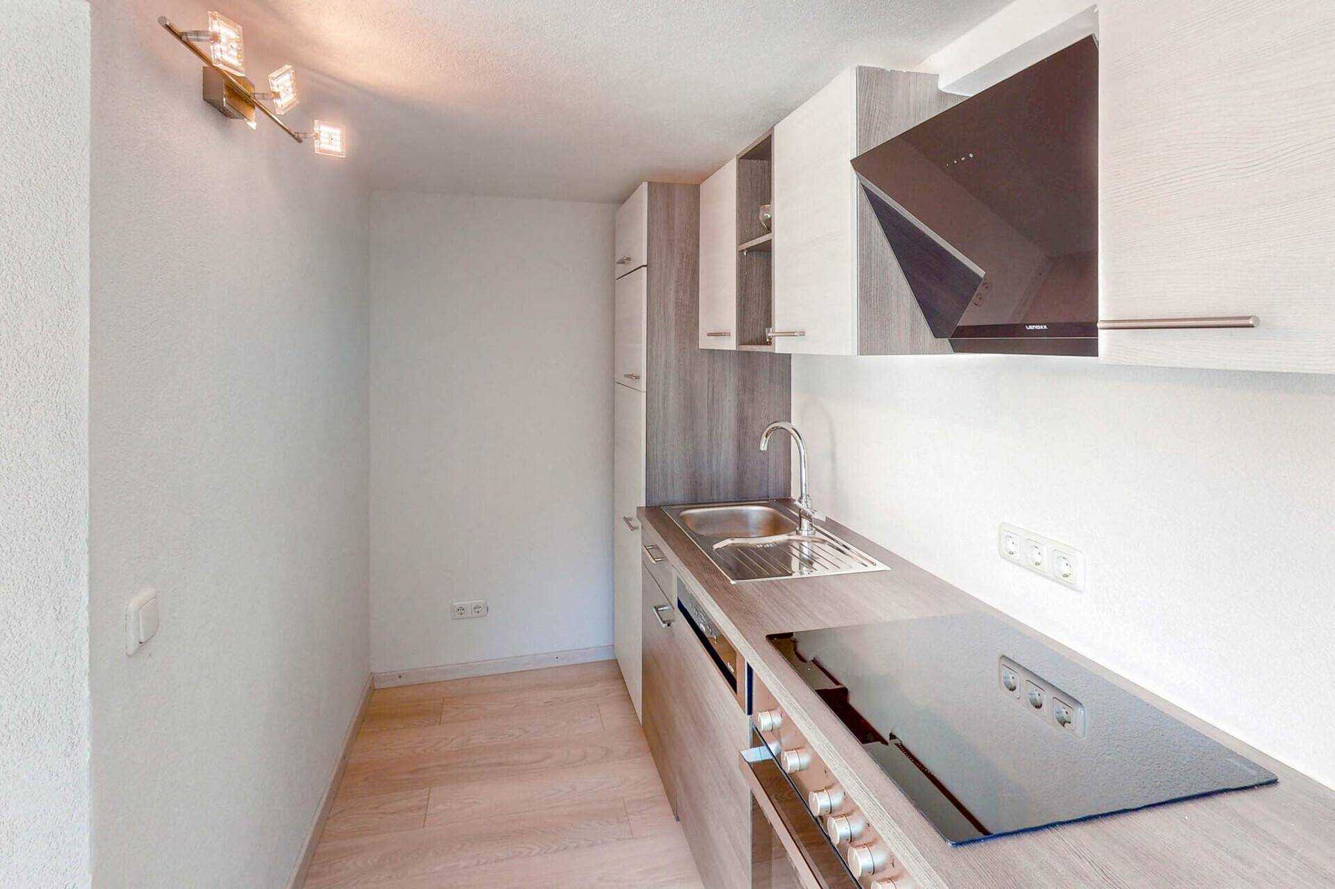Moderne Einbauküche mit Induktionskochfeld und Dunstabzugshaube.