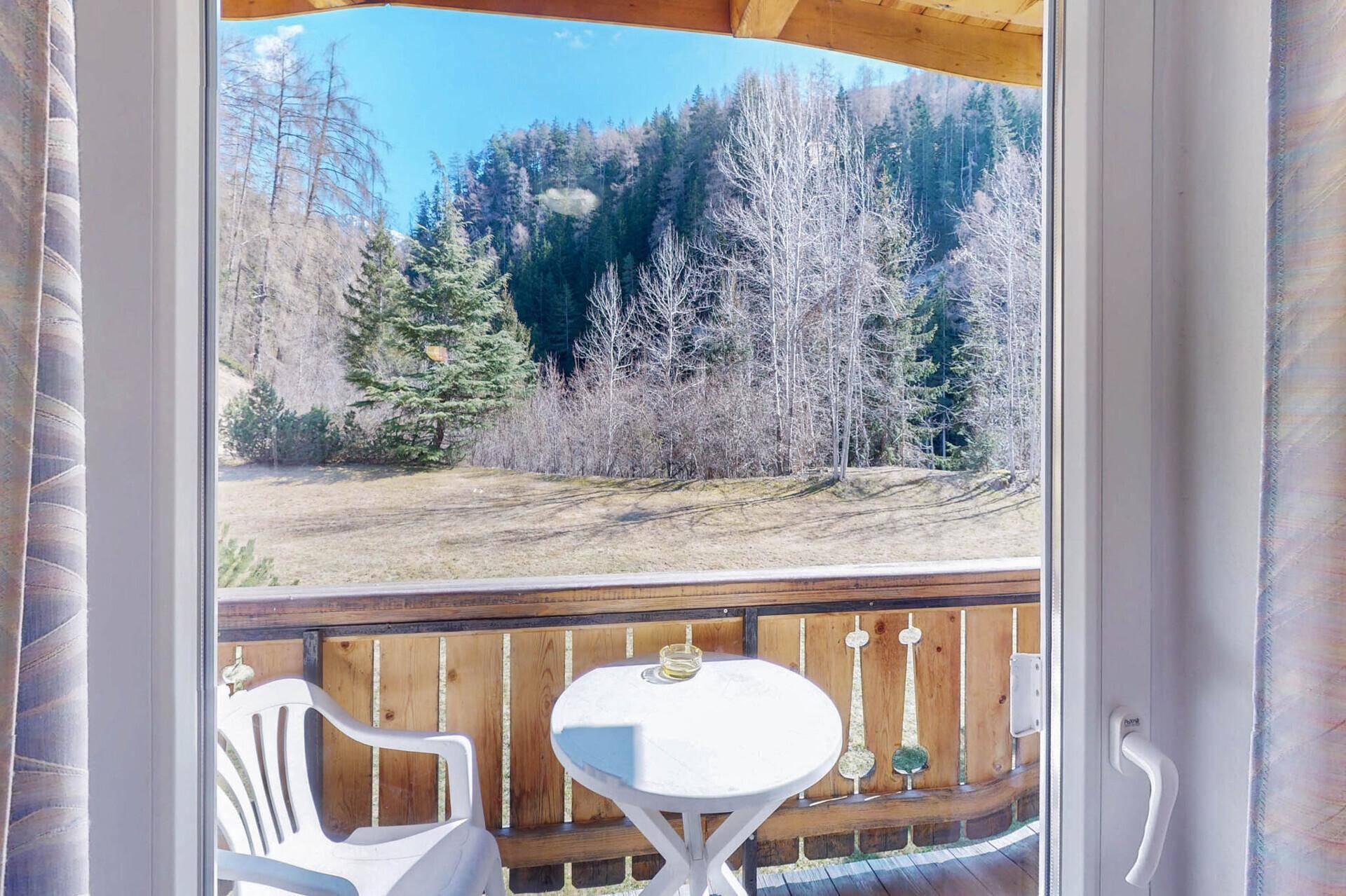 Kleiner Balkon mit Sitzgelegenheiten und weitem Blick auf die bewaldeten Berge.