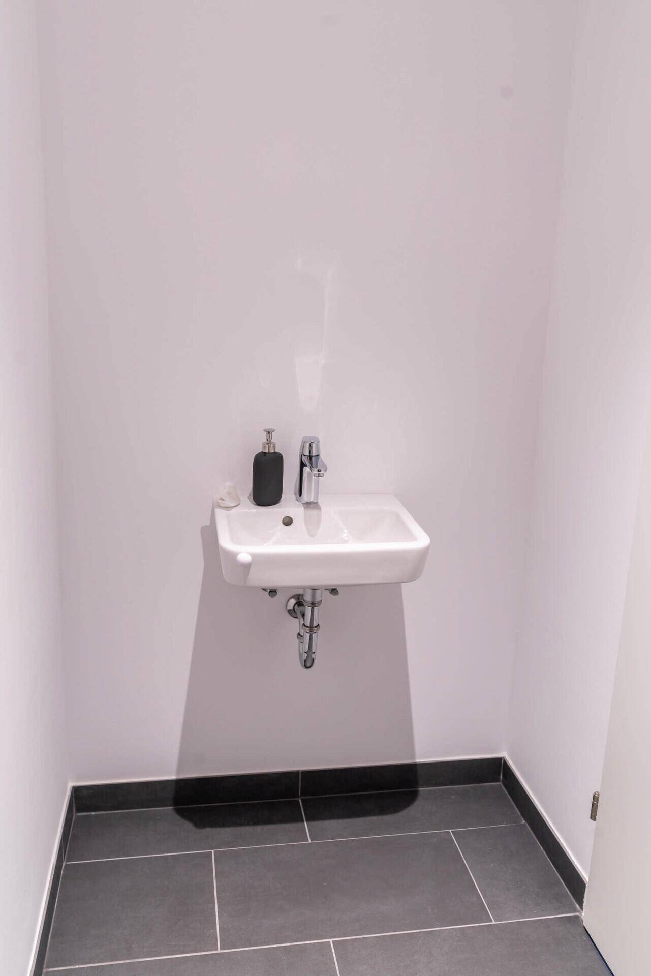 Modernes Badezimmer mit begehbarer Dusche, Holzwaschtisch und beleuchtetem Spiegel.