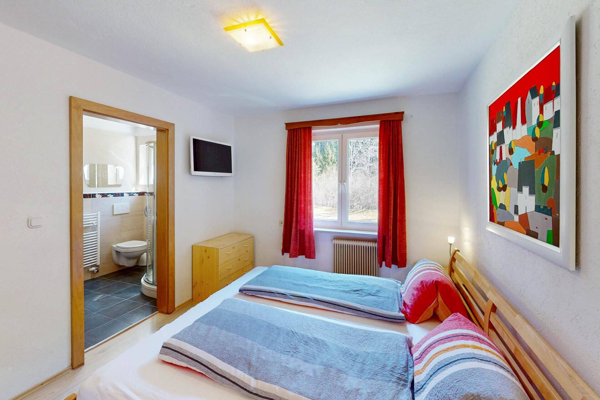 Schlafzimmer mit Doppelbett und direktem Zugang zu einem modernen Badezimmer.