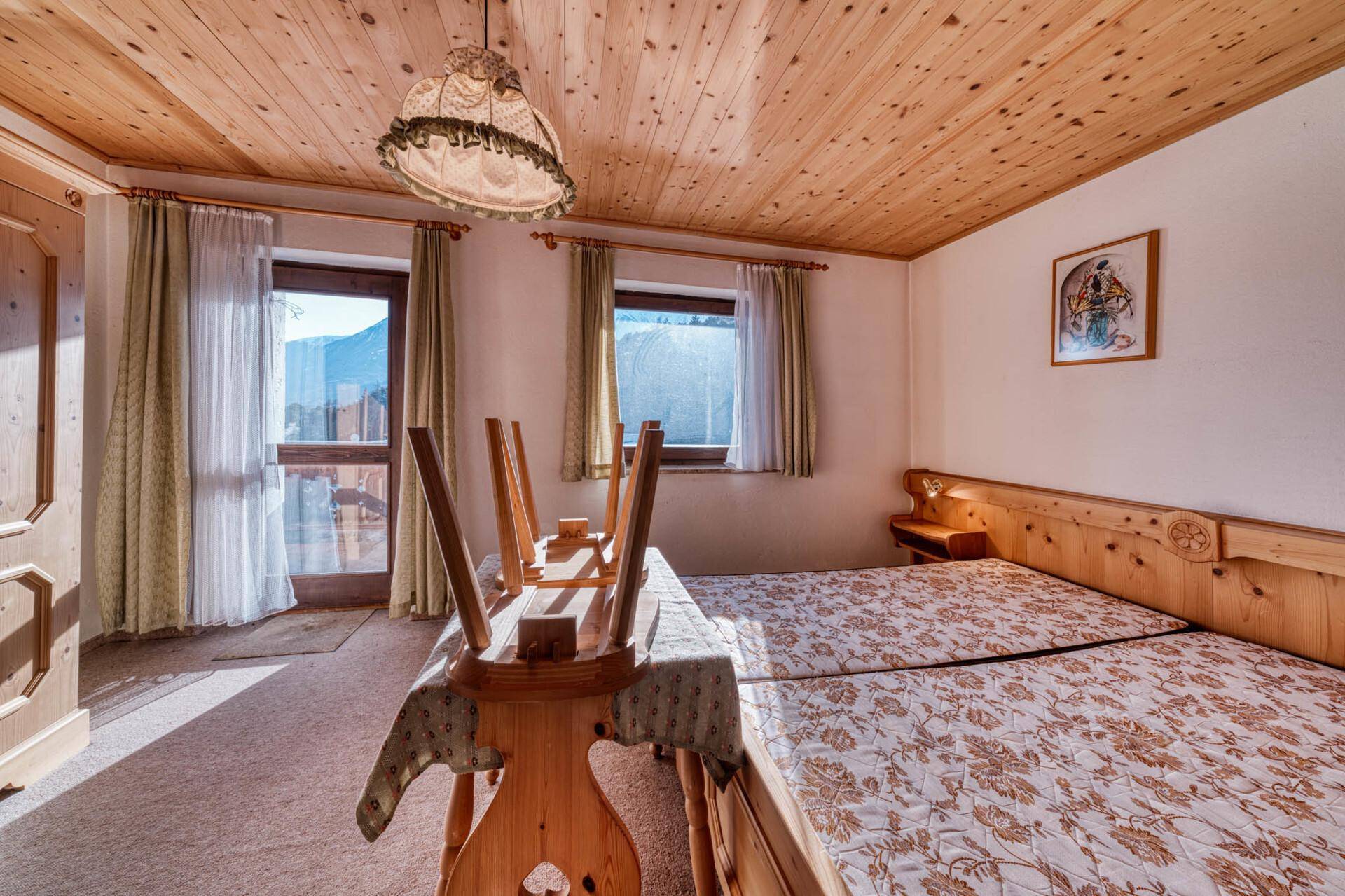 Schlafzimmer mit Zugang zum Balkon, Holzdecke und traditionellen Betten.