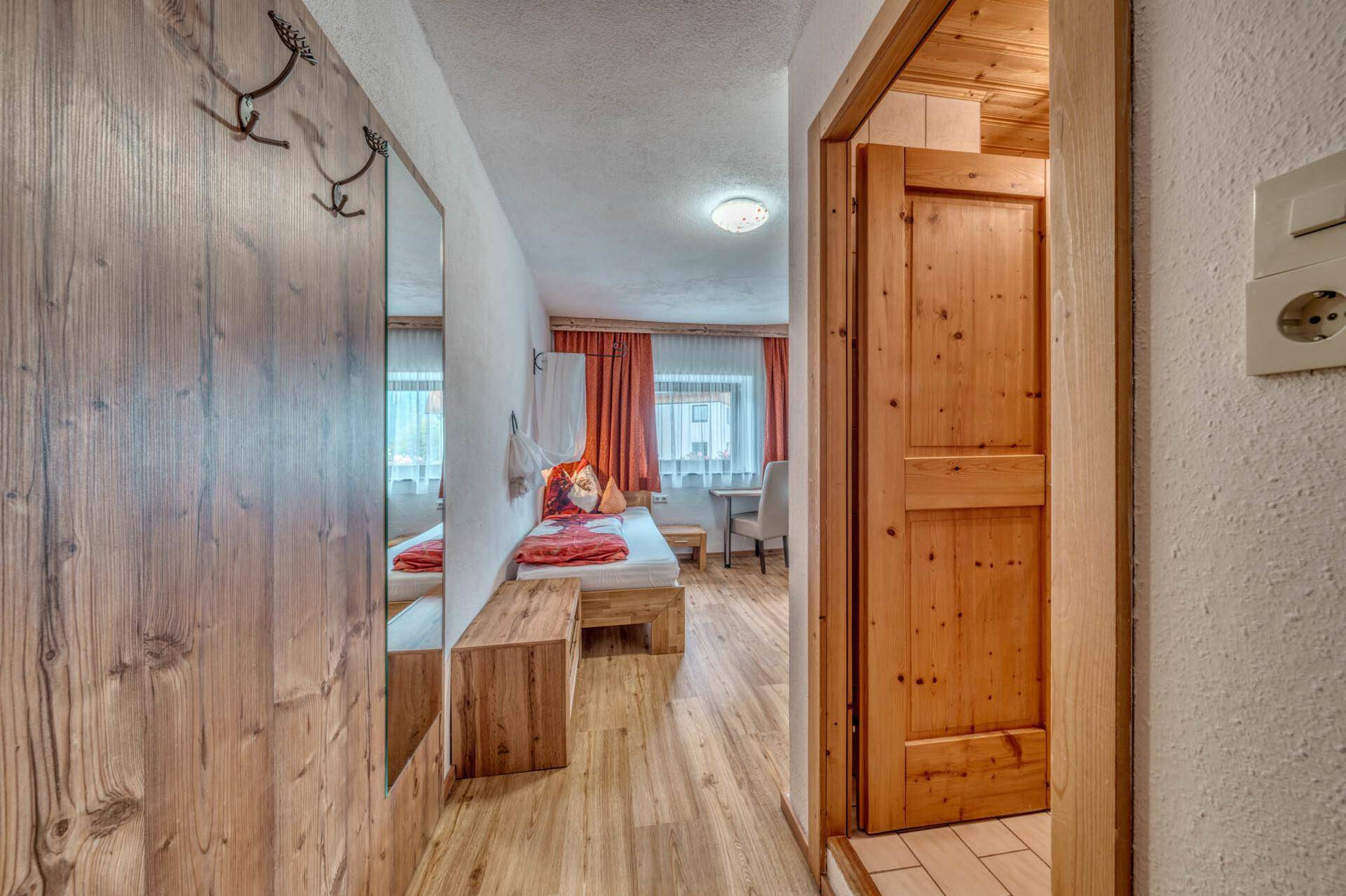 Flur mit Holztüren und Blick in ein helles Schlafzimmer, praktisch und funktional.