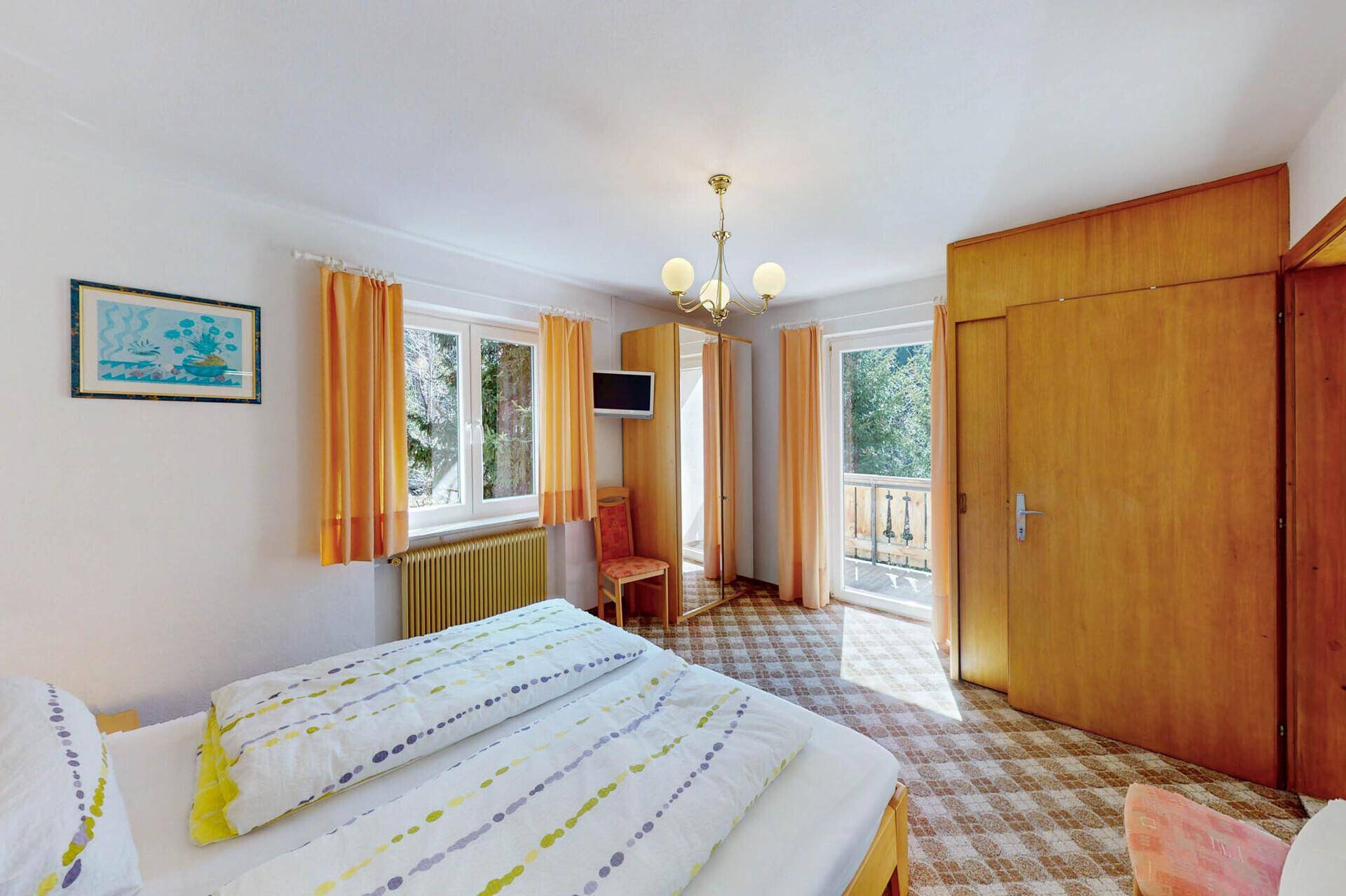 Helles Schlafzimmer mit Doppelbett, Teppichboden und Balkonzugang.