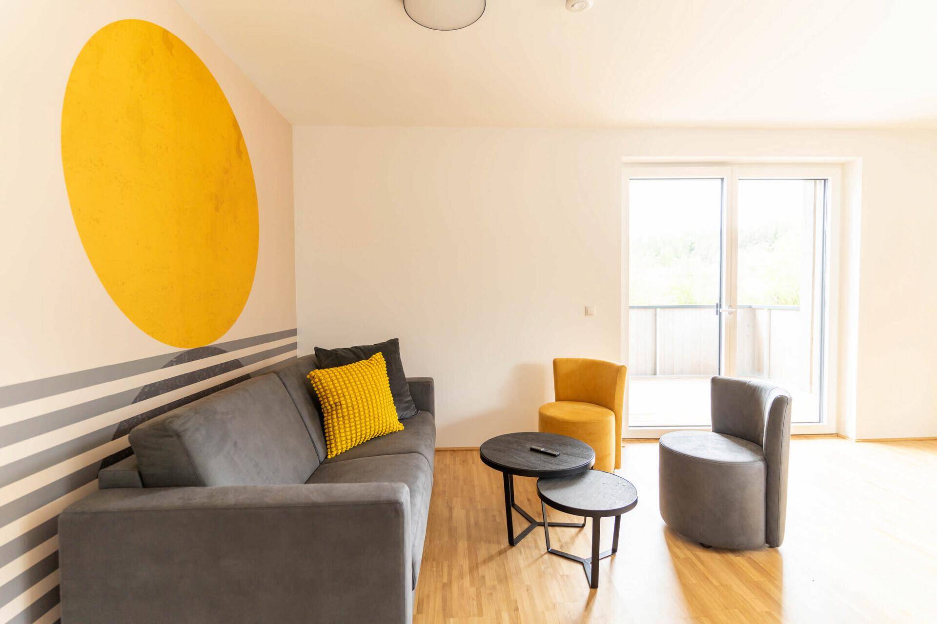 Moderne Küche mit grauen Fronten, Holzarbeitsplatte und Esstisch im offenen Bereich.