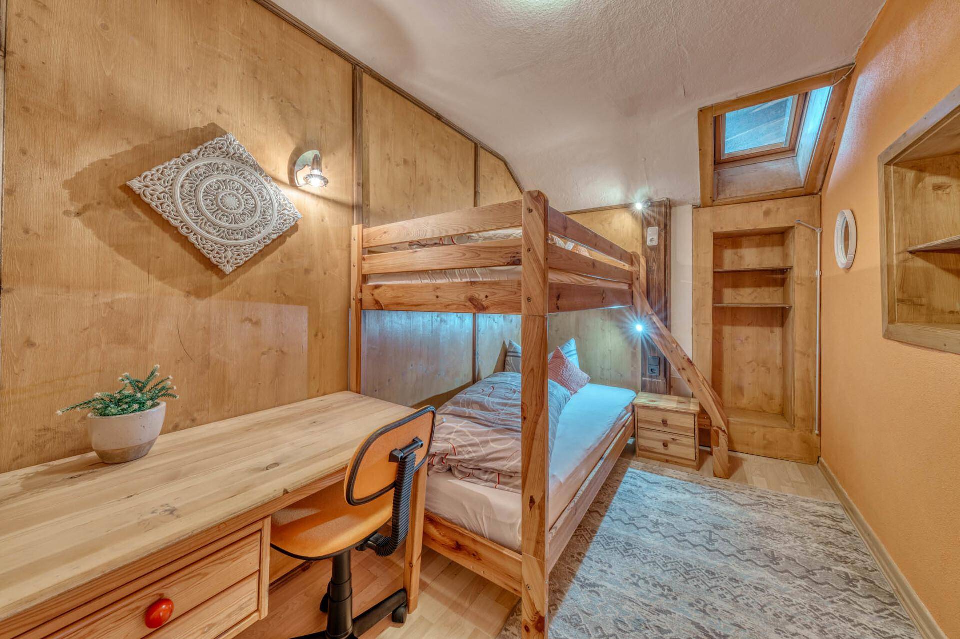Kinderzimmer mit Etagenbett, Schreibtisch und Holzvertäfelung.