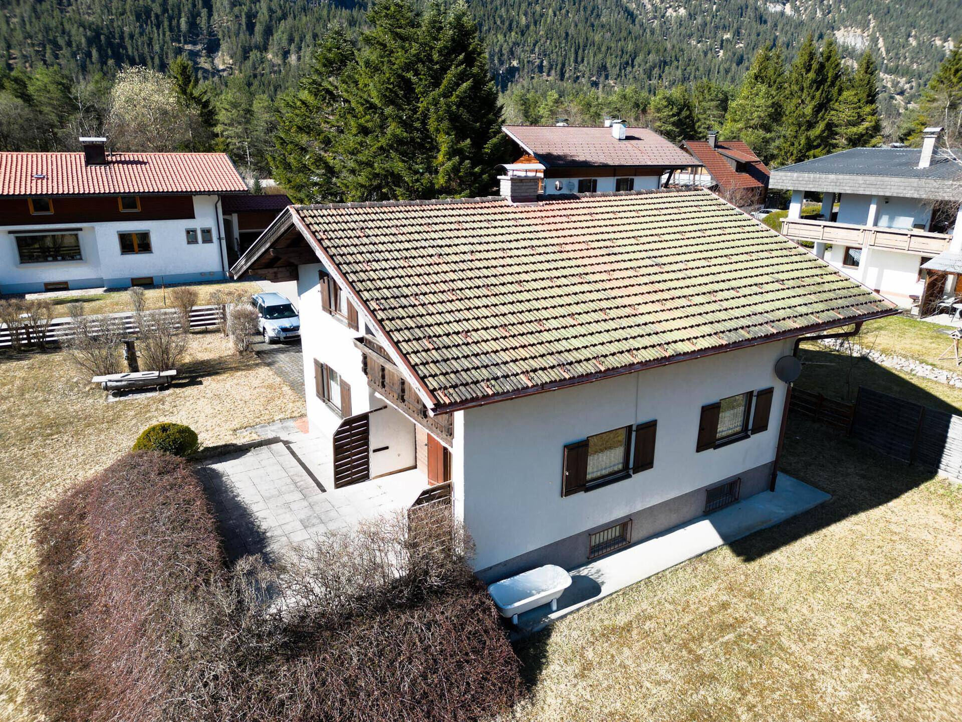 Luftaufnahme des Hauses mit Garten, Terrasse und Bergblick.