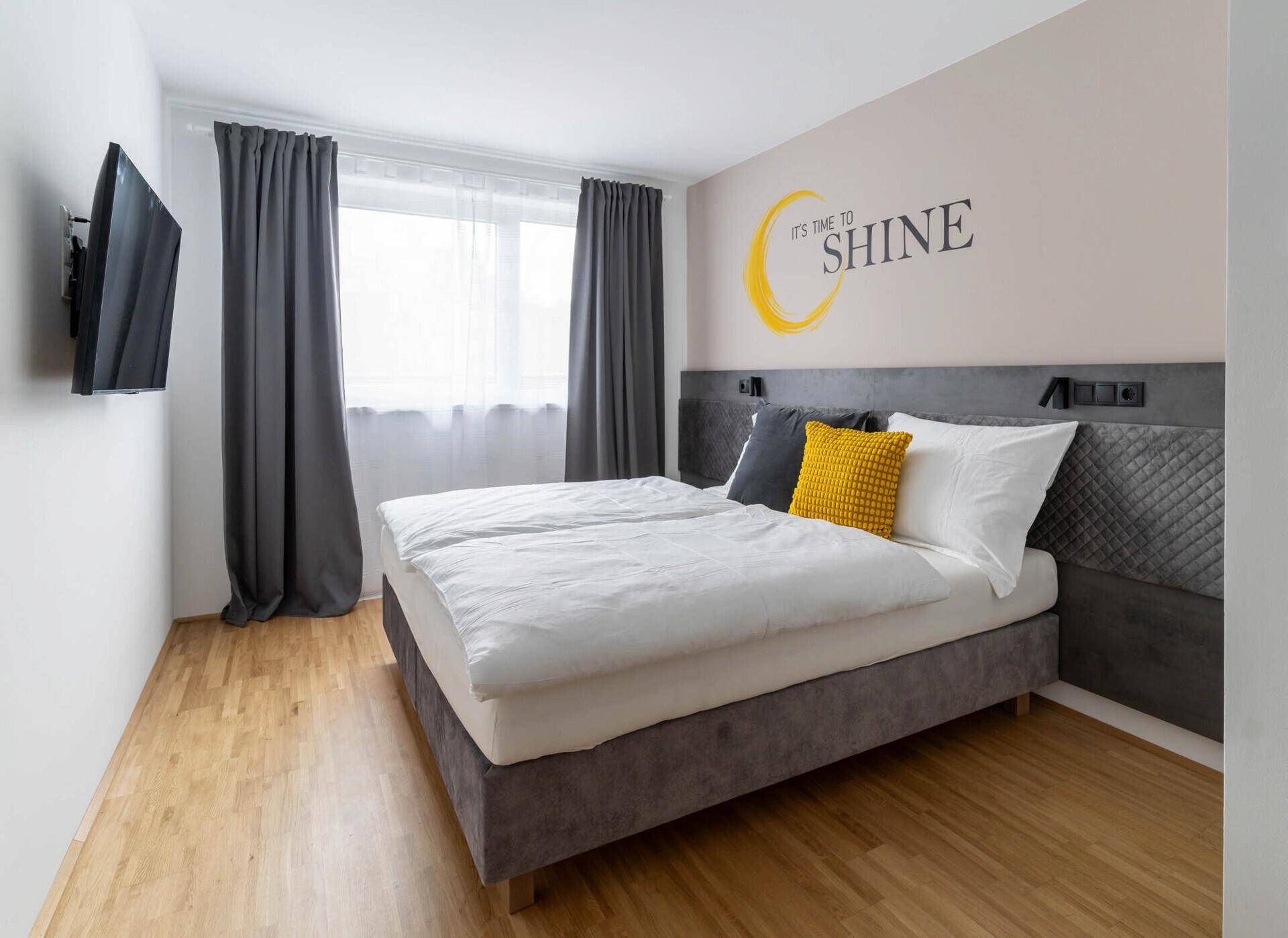 Detailansicht des Bettes mit Kissen und Wandleuchte im Schlafzimmer.