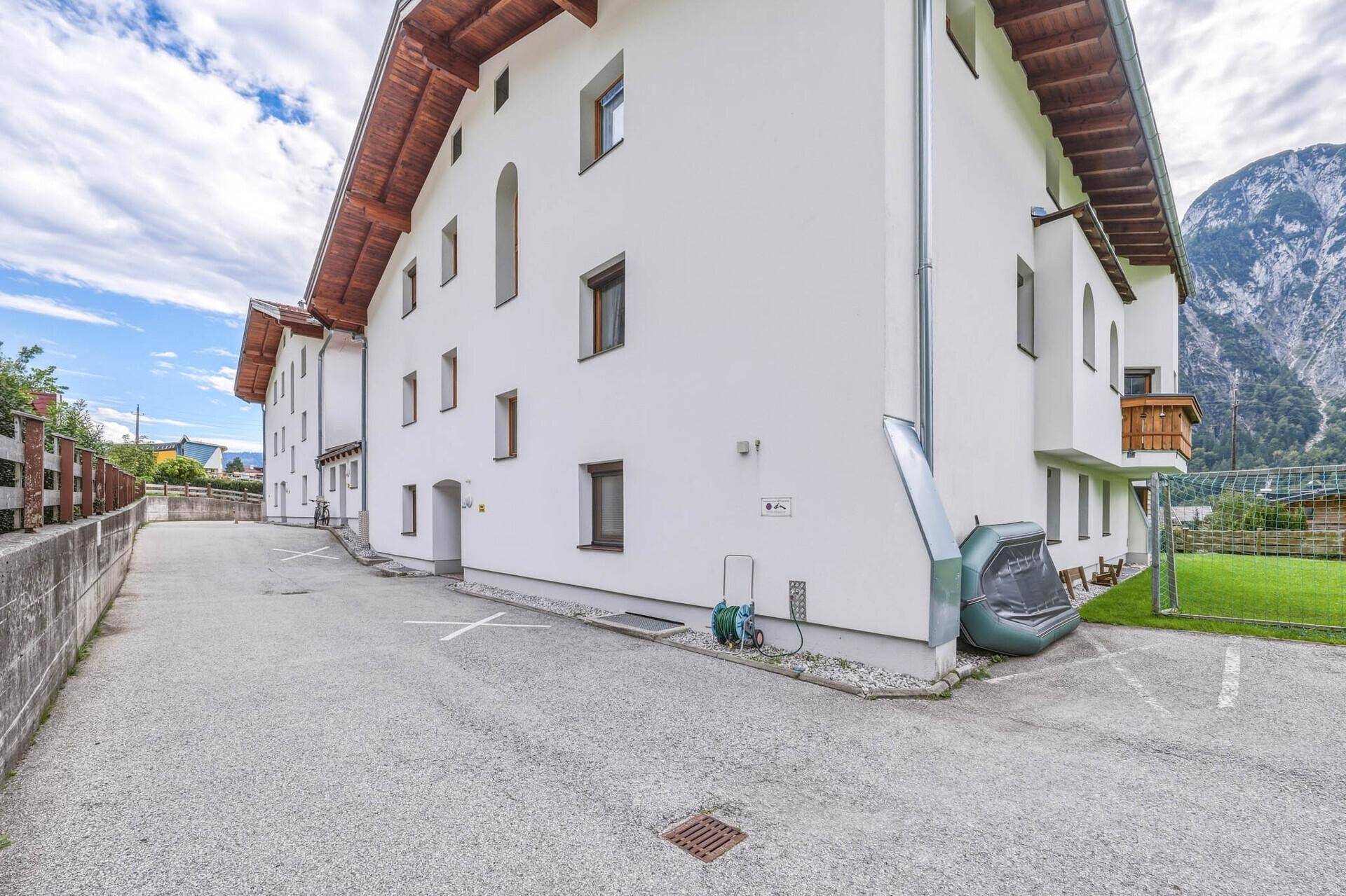 Seitenansicht des Gebäudes mit gepflastertem Parkplatz und Zugang zum Eingangsbereich.