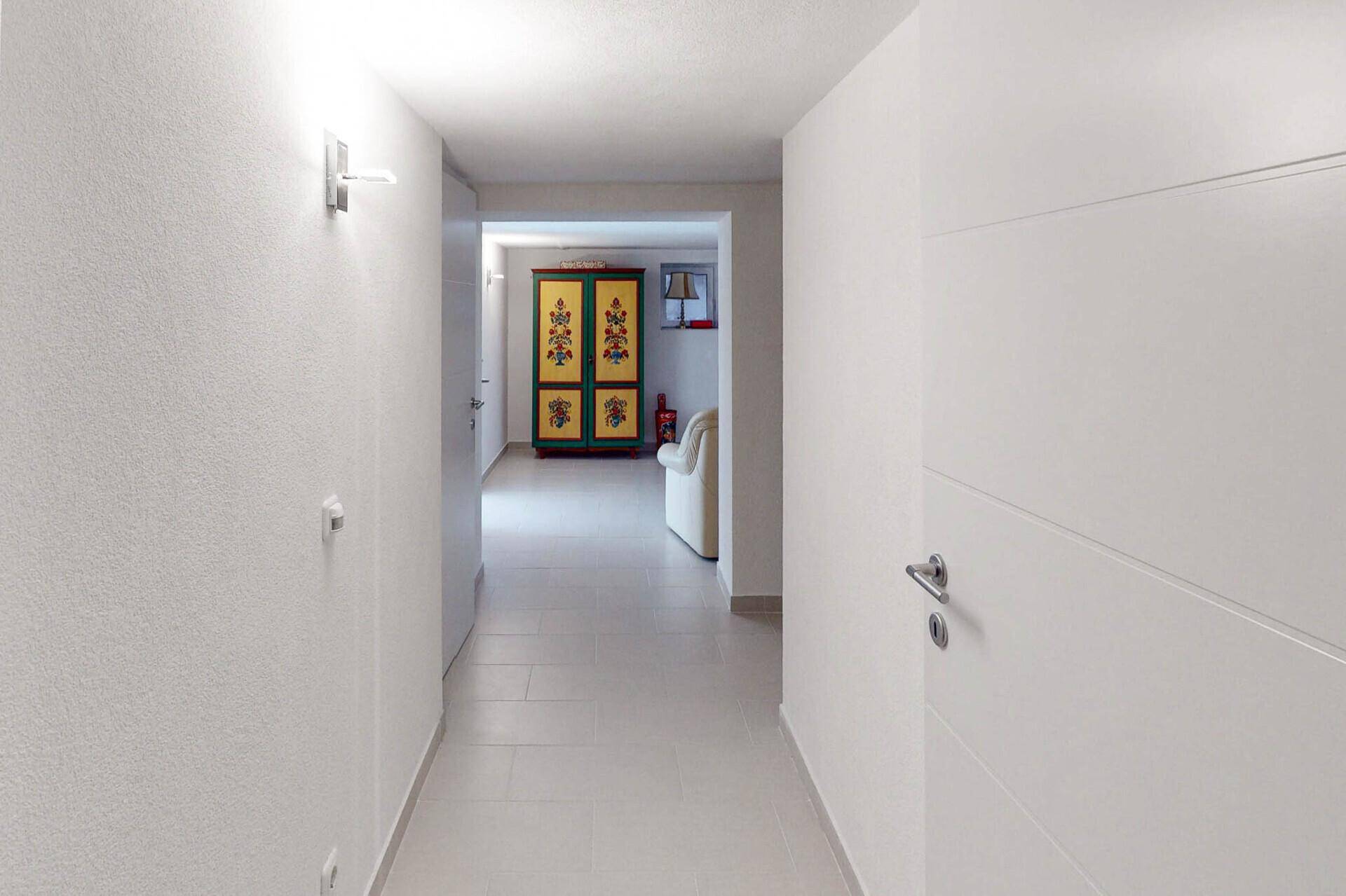 Heller Flur im Kellergeschoss mit Fliesenboden und Zugang zu weiteren Räumen.