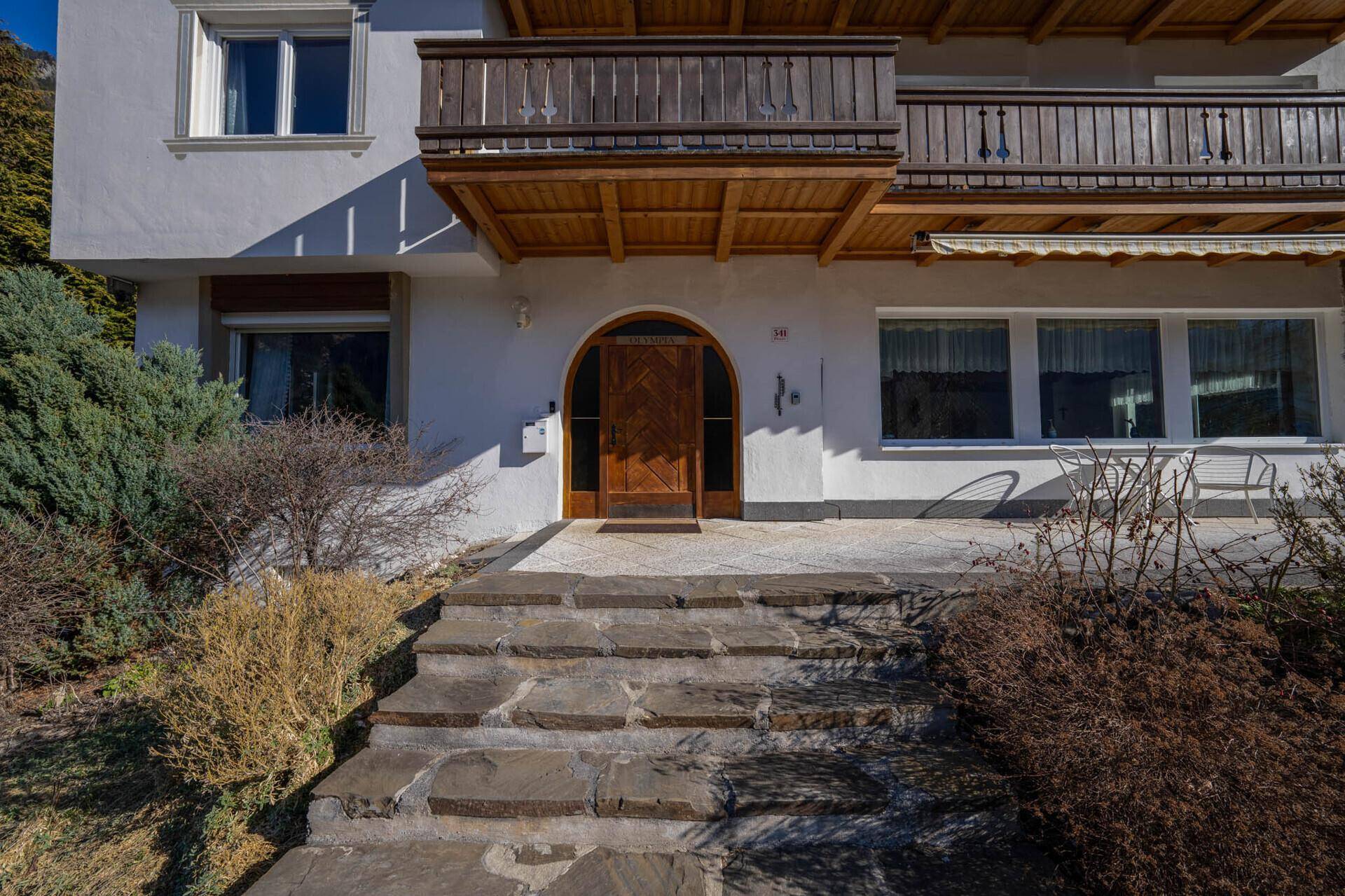 Eingangsbereich des Hauses mit Steintreppe und traditioneller Holztür.