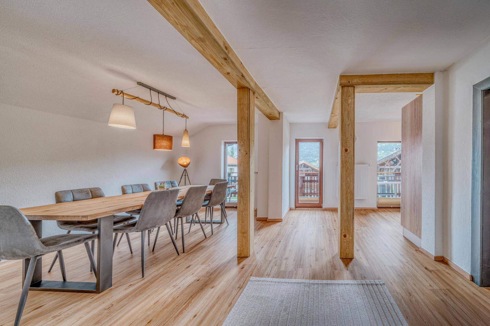 Geräumiger Essbereich mit Holzbalken, modernem Esstisch und hellem Holzboden.