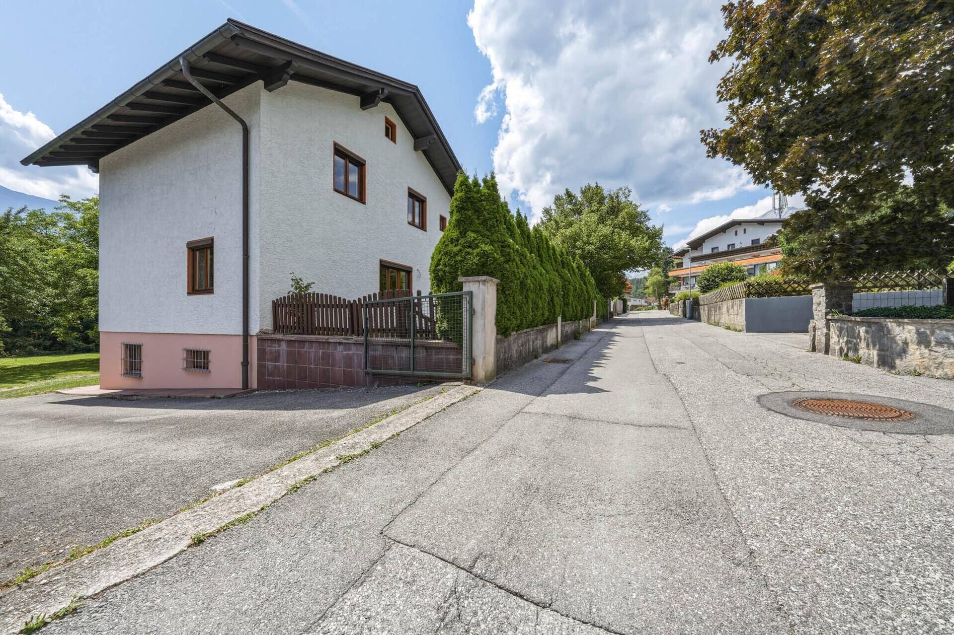 Straßenansicht des Hauses mit gepflegter Hecke und Bergblick in der Ferne.