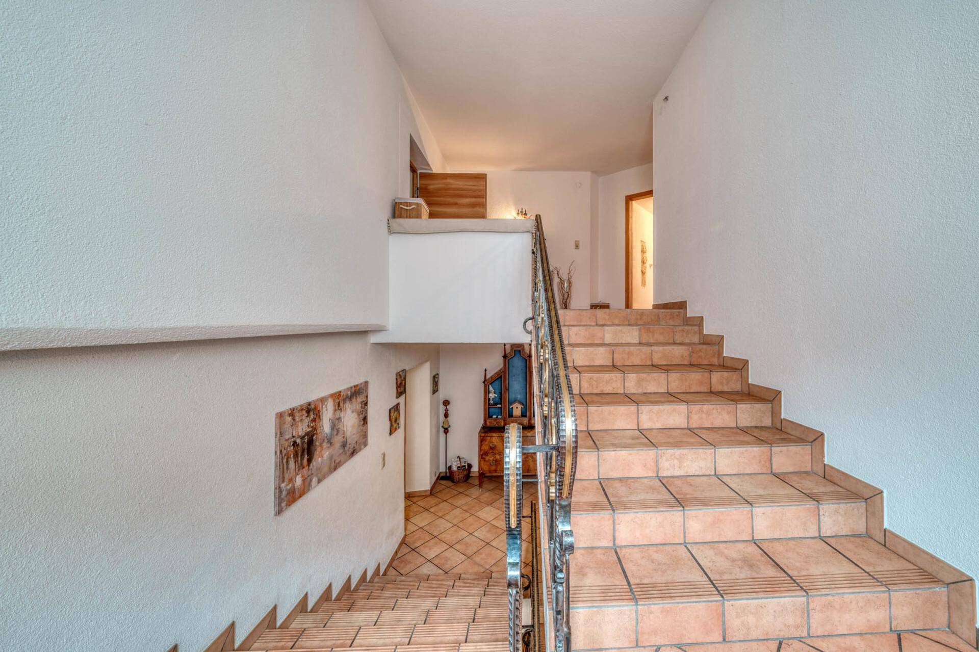 Treppenhaus mit gefliesten Stufen und Metallgeländer, das die Etagen verbindet.