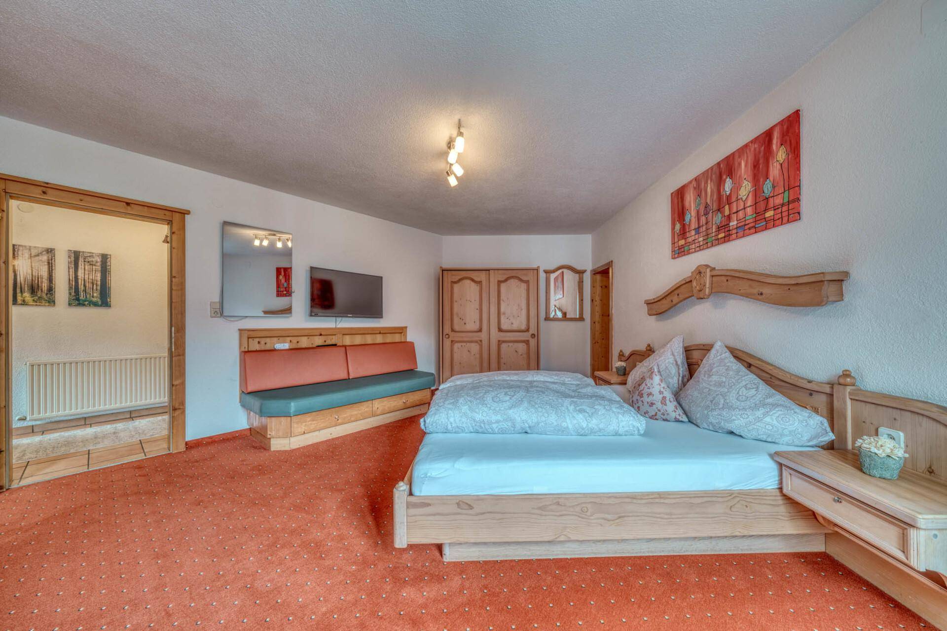 Komfortables Schlafzimmer mit Doppelbett, Sitzgelegenheit und Fernseher.