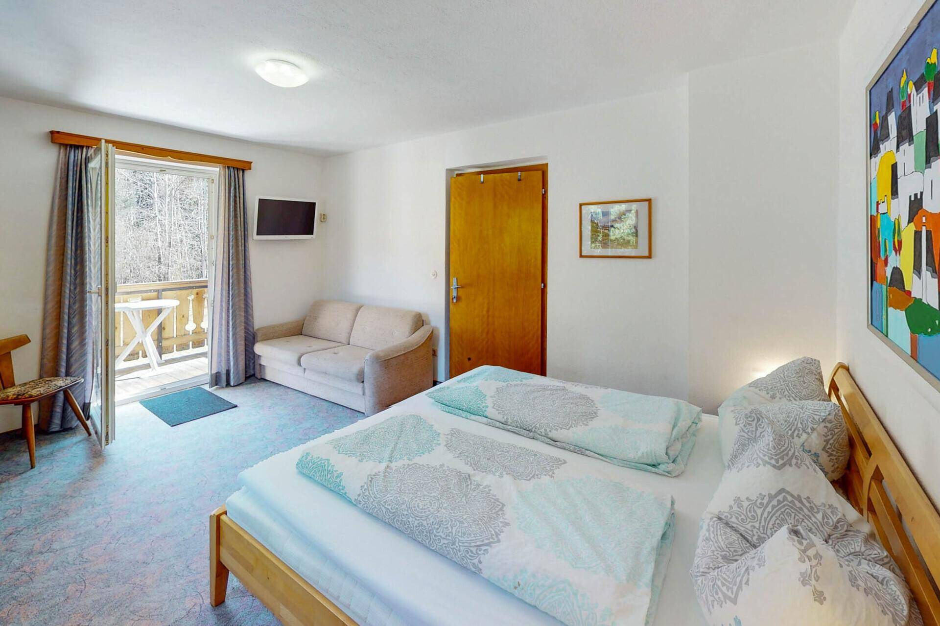 Geräumiges Schlafzimmer mit Doppelbett, Sofa und Balkonzugang.