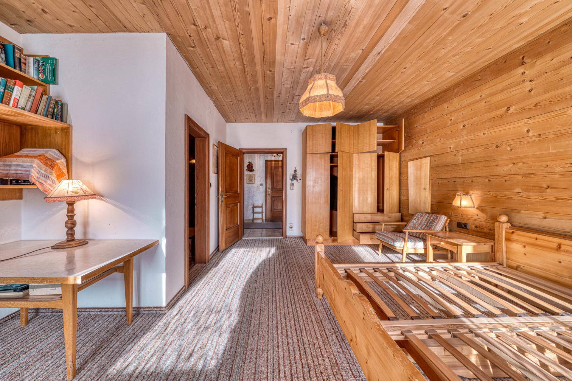 Geräumiges Schlafzimmer mit Holzvertäfelung, Teppichboden und Zugang zu weiteren Räumen.