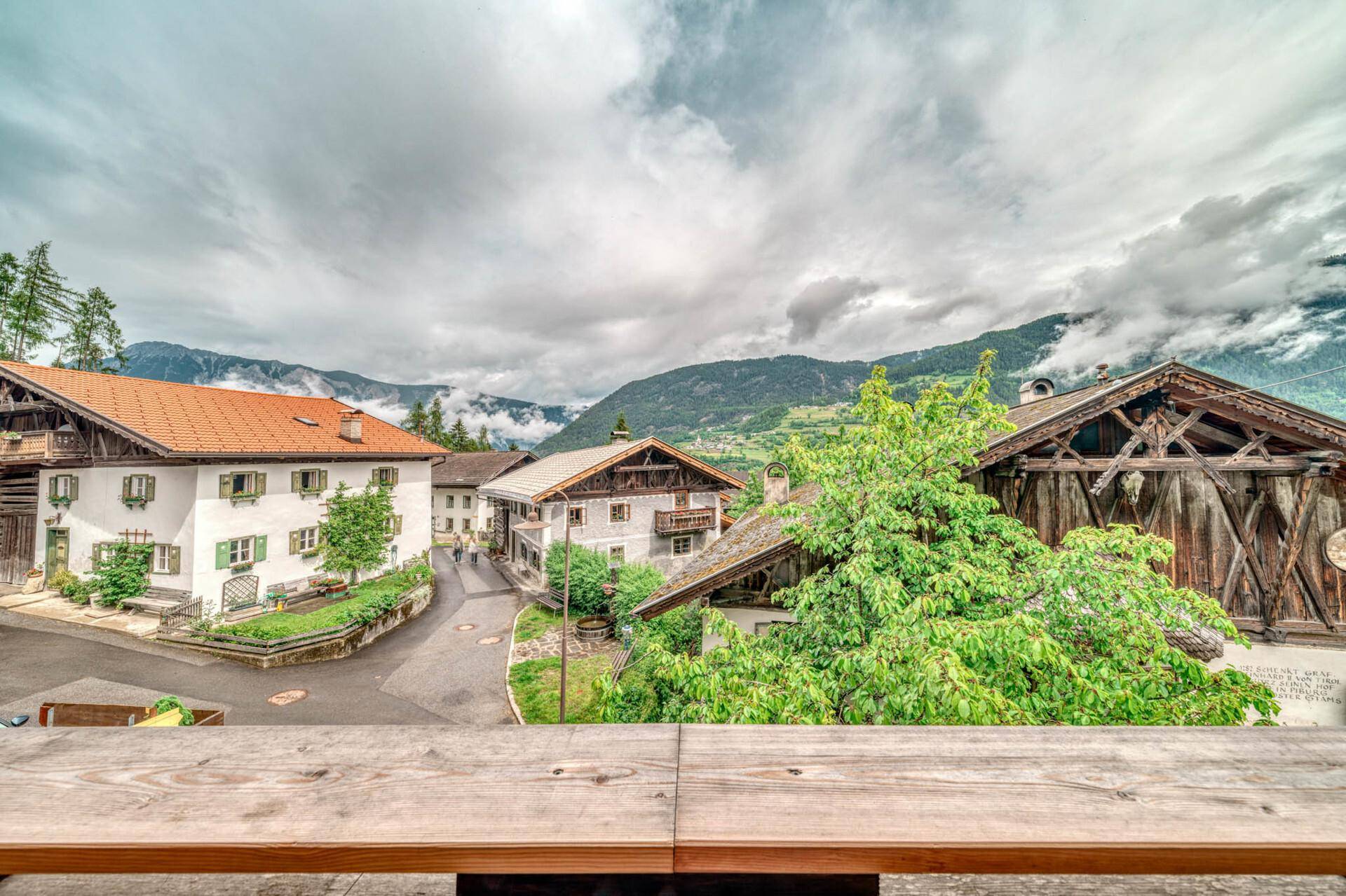 Panoramablick vom Balkon auf das charmante Bergdorf und die majestätischen Alpen.