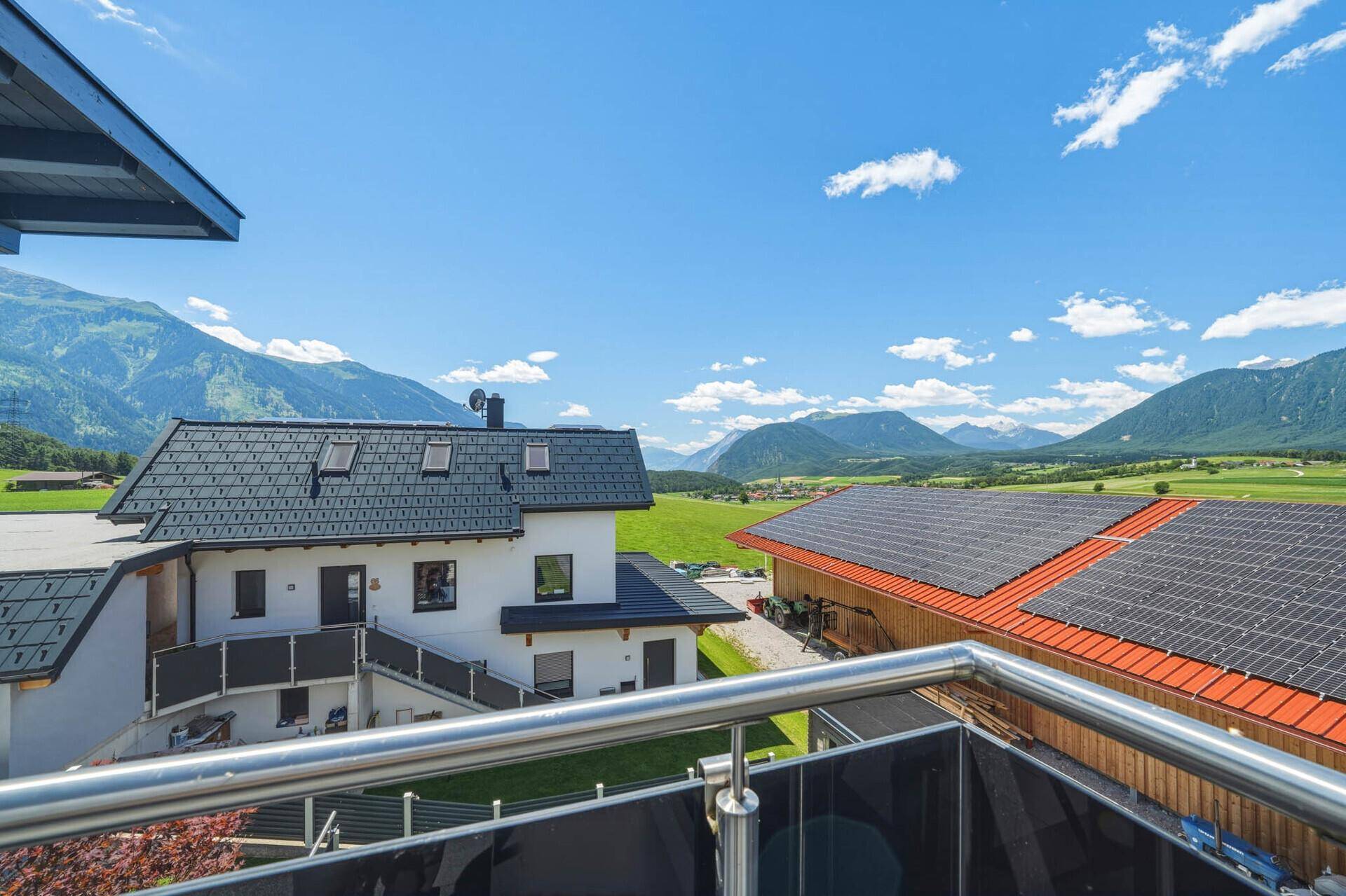Panoramablick auf die grüne Landschaft, Berge und benachbarte Gebäude mit Solaranlagen.