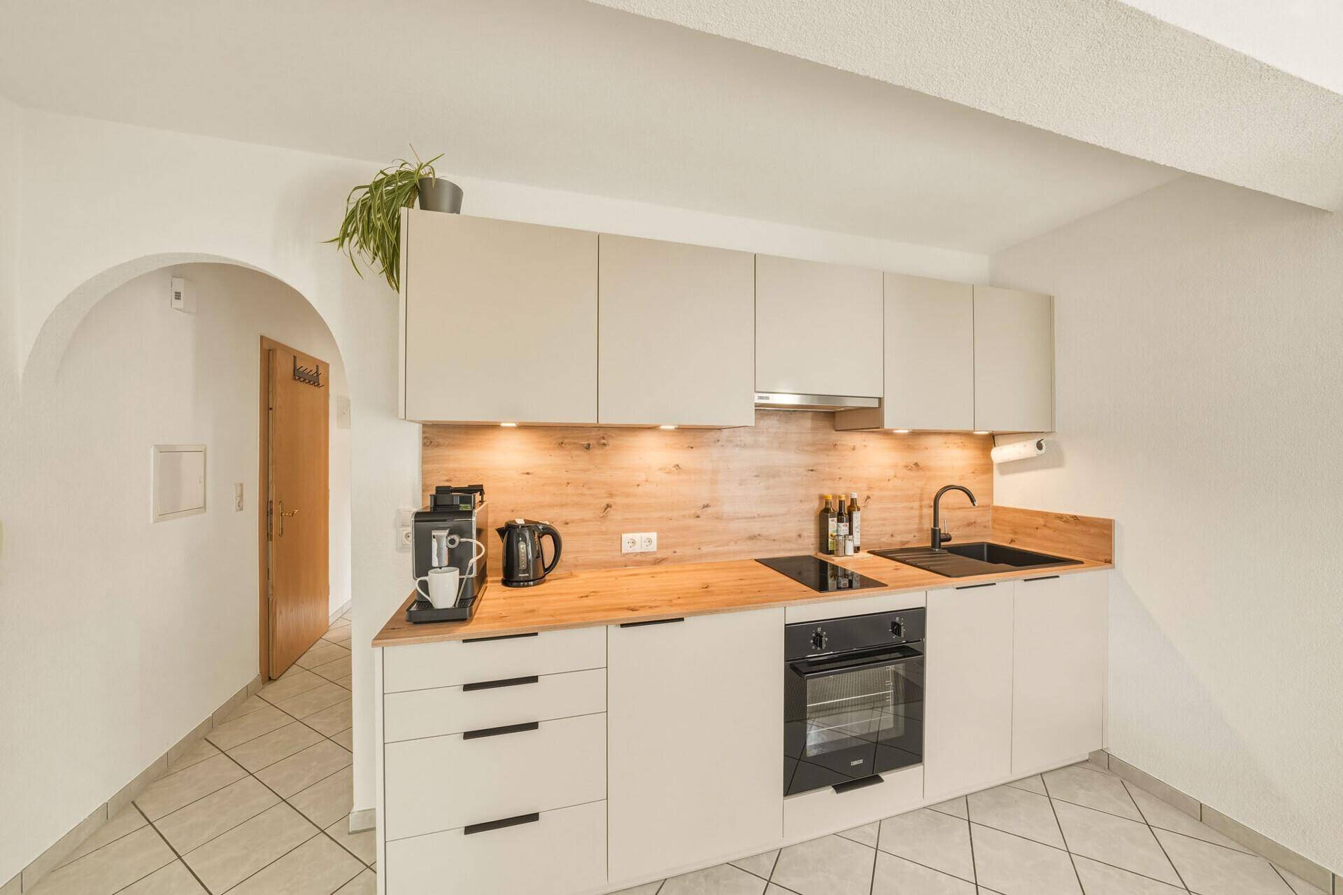 Moderne Einbauküche mit hellen Schränken, Holzdetails und integrierten Geräten.