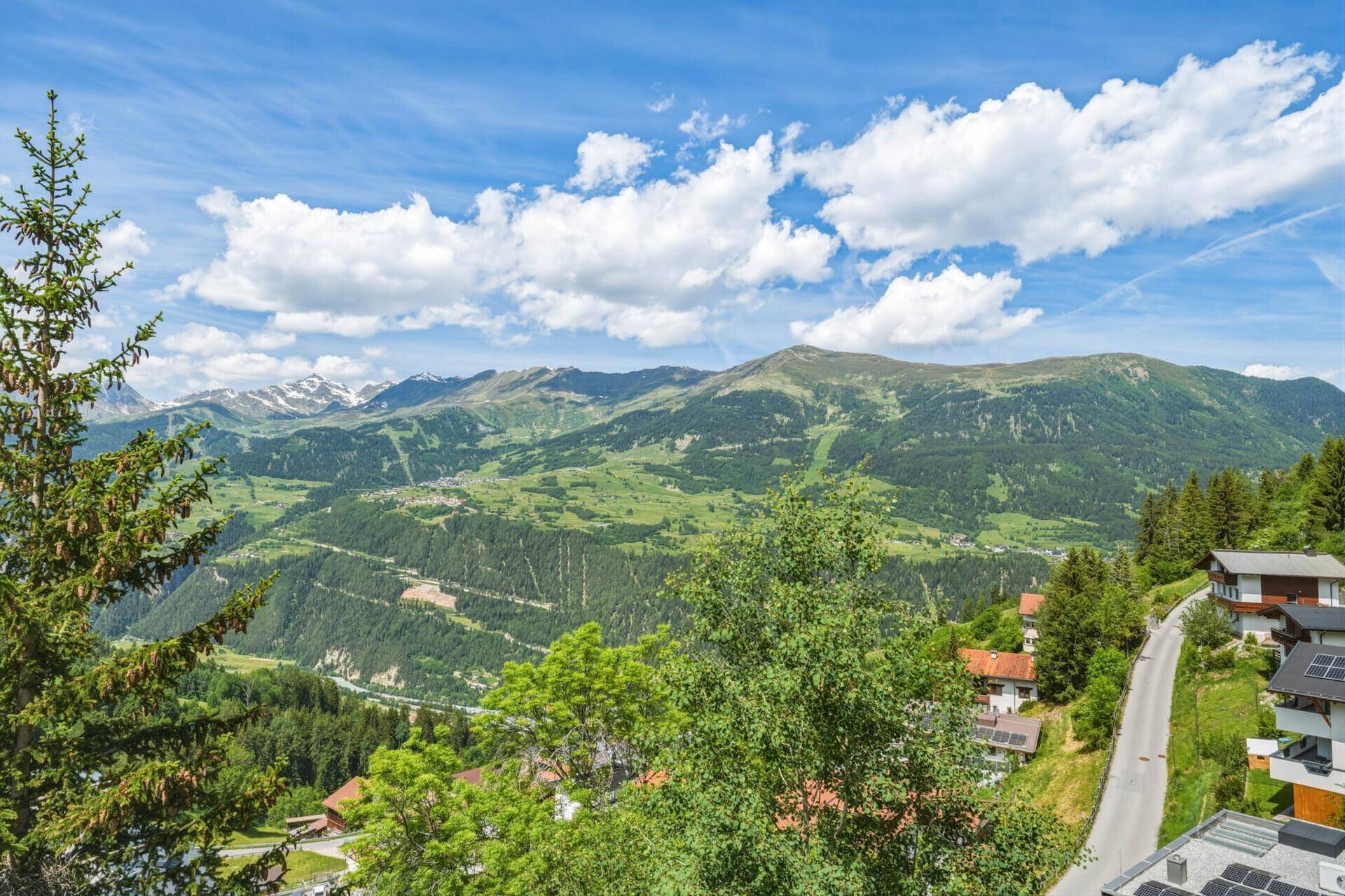 Weitläufiger Panoramablick auf die grüne Berglandschaft mit Tälern und bewaldeten Hängen.