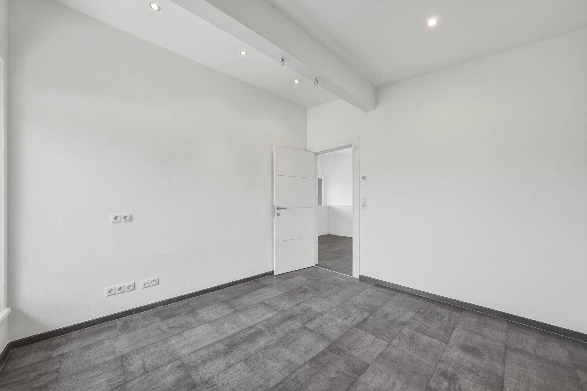 Modernes Zimmer mit grauen Fliesen und weiß gestrichenen Wänden, ideal als Schlaf- oder Gästezimmer.