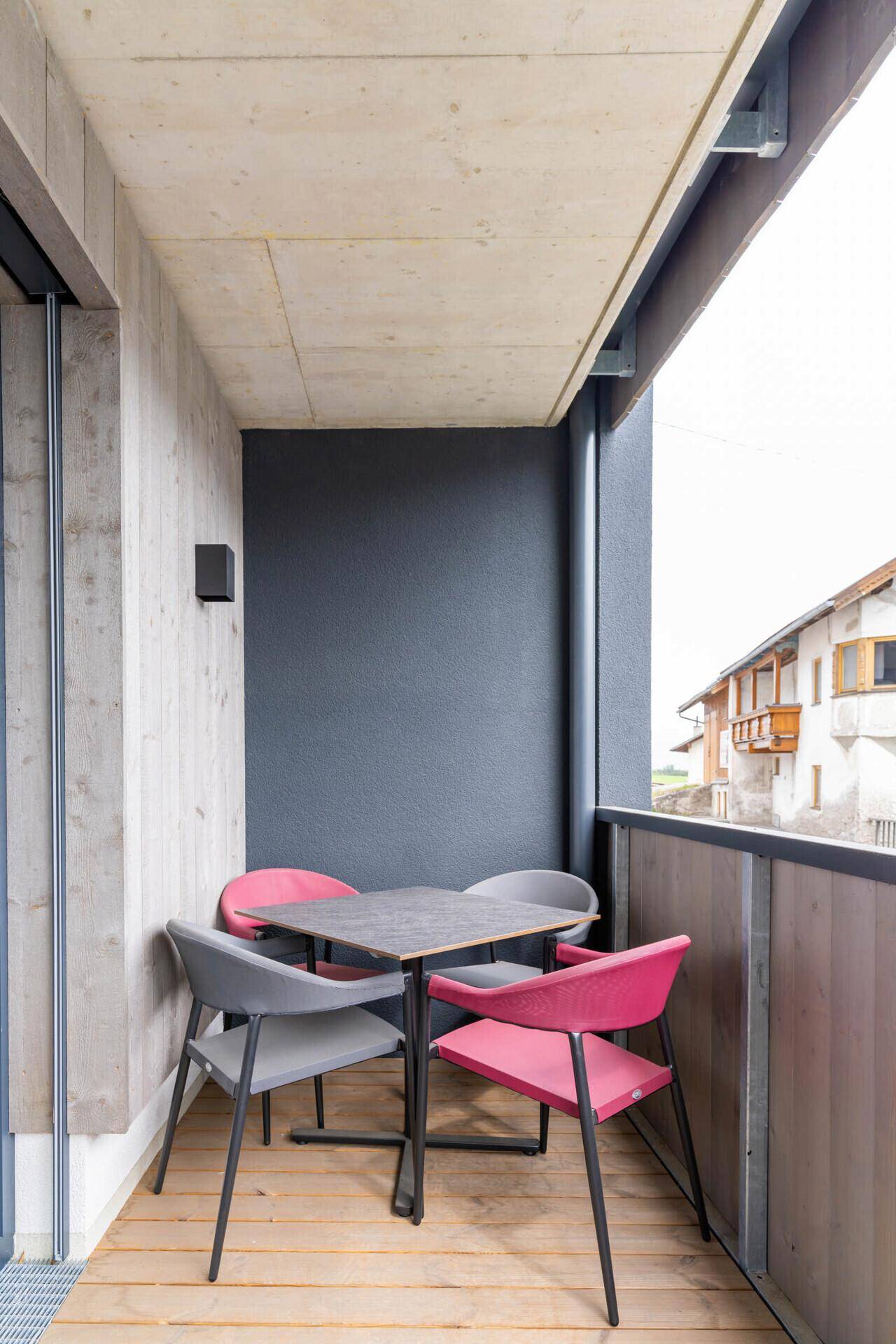 Überdachter Balkon mit Holzboden und Sitzgelegenheiten, ideal für entspannte Stunden.