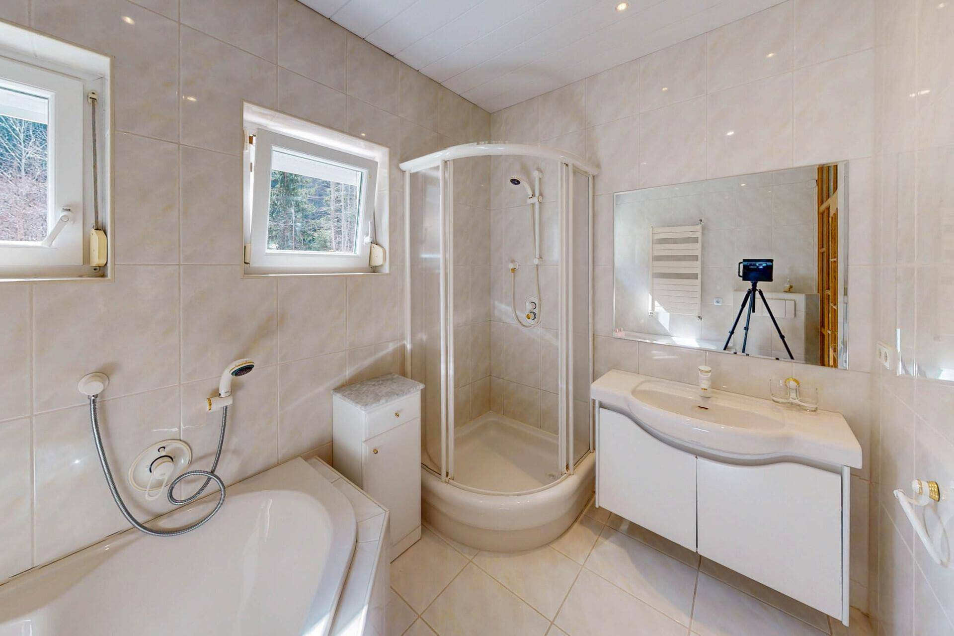 Badezimmer mit Badewanne, Duschkabine, Einzelwaschbecken und Fenster.