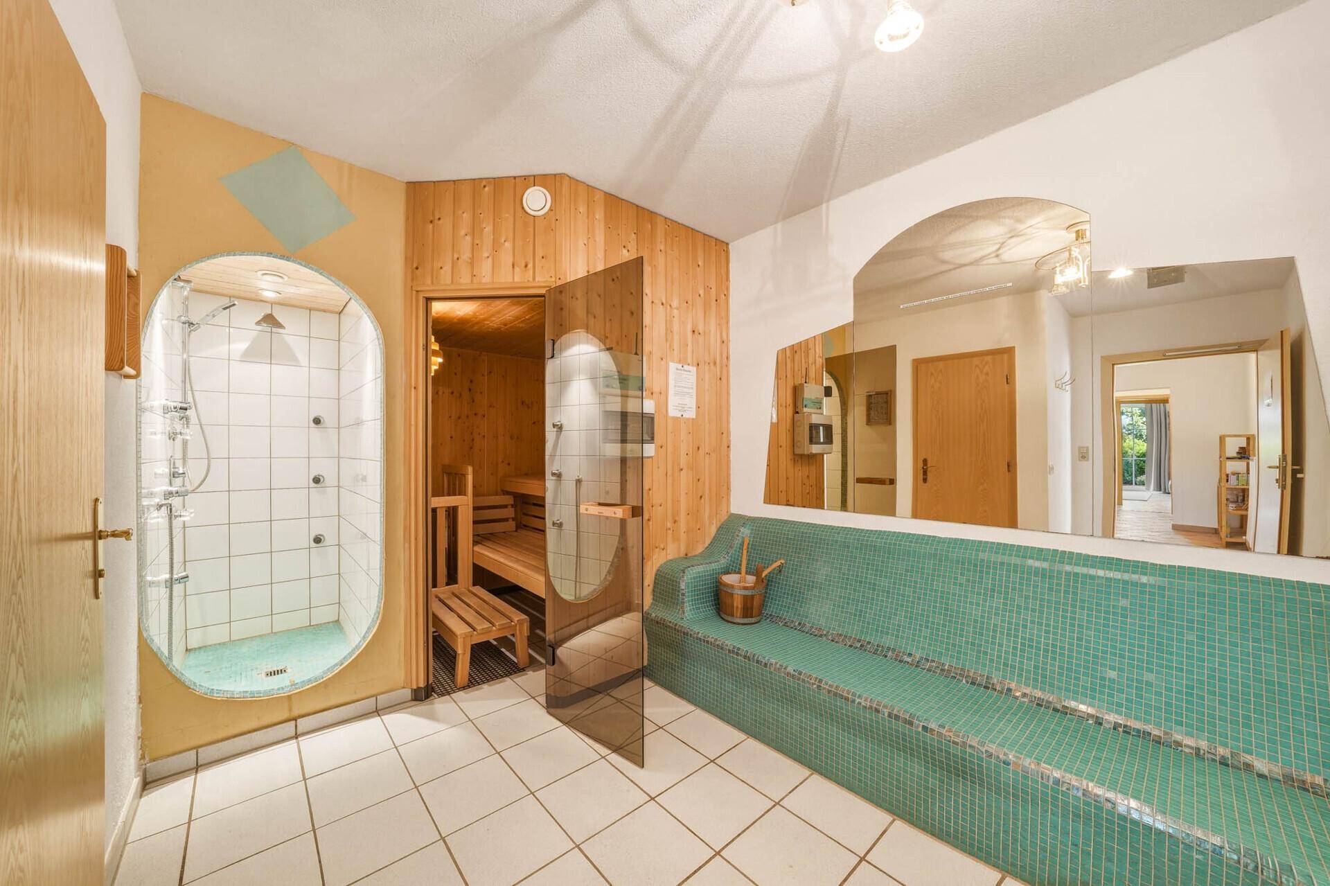 Wellnessbereich mit Sauna, Duschkabine und einer gefliesten Entspannungsbank.