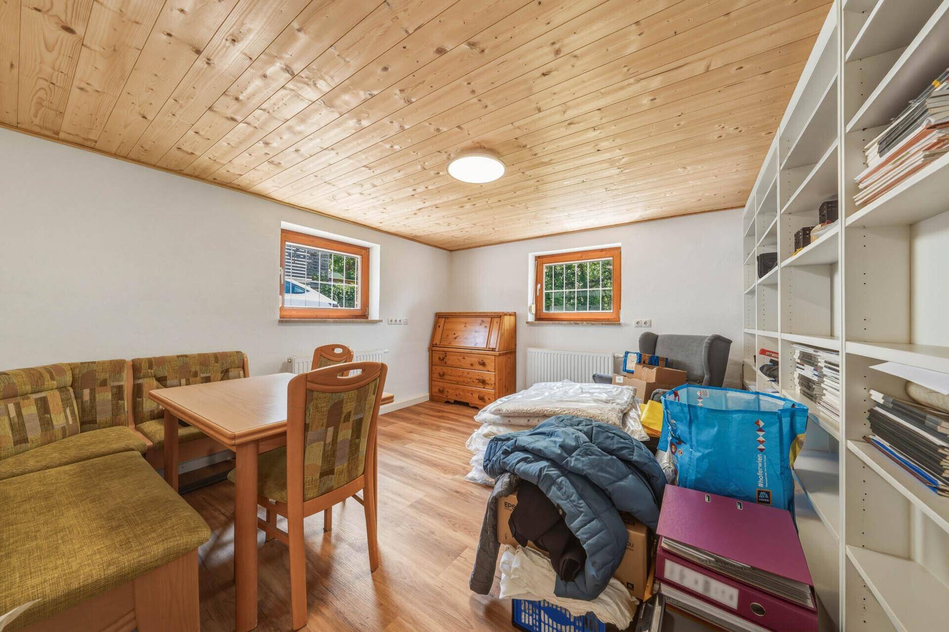 Vielseitiger Raum mit Holzdecke, Essbereich und Stauraum, ideal für Freizeitaktivitäten.