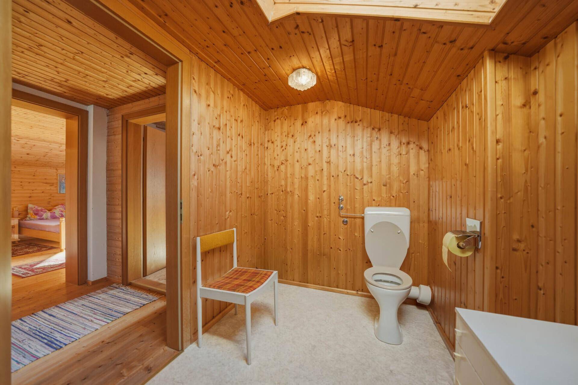 Kleines WC mit Holztäfelung, Dachschräge und einfacher Ausstattung.