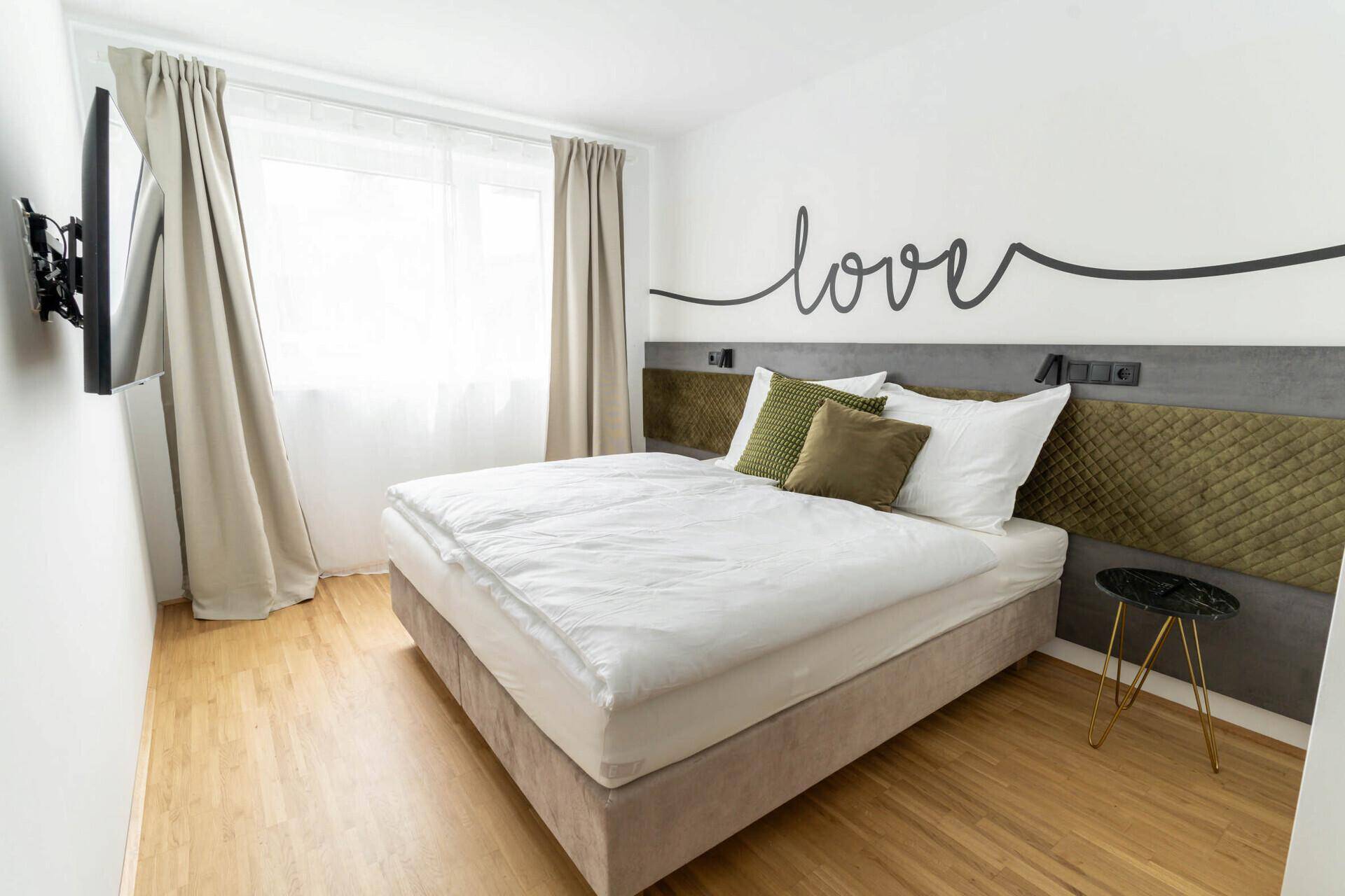 Gemütliches Schlafzimmer mit Doppelbett, Holzboden und dekorativer Wandgestaltung.