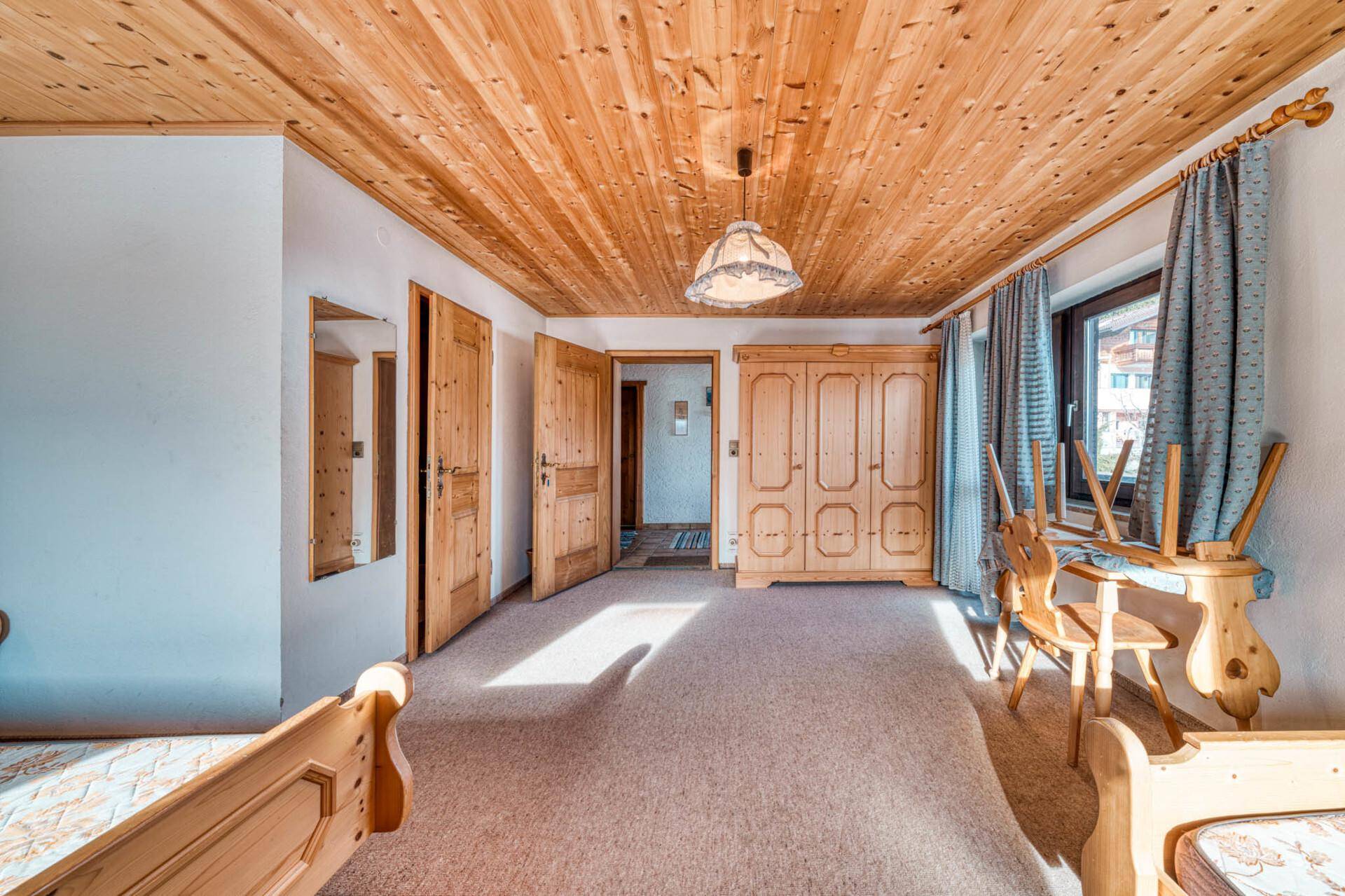 Geräumiges Schlafzimmer mit Holzdecke, Teppichboden und traditionellen Holzmöbeln.