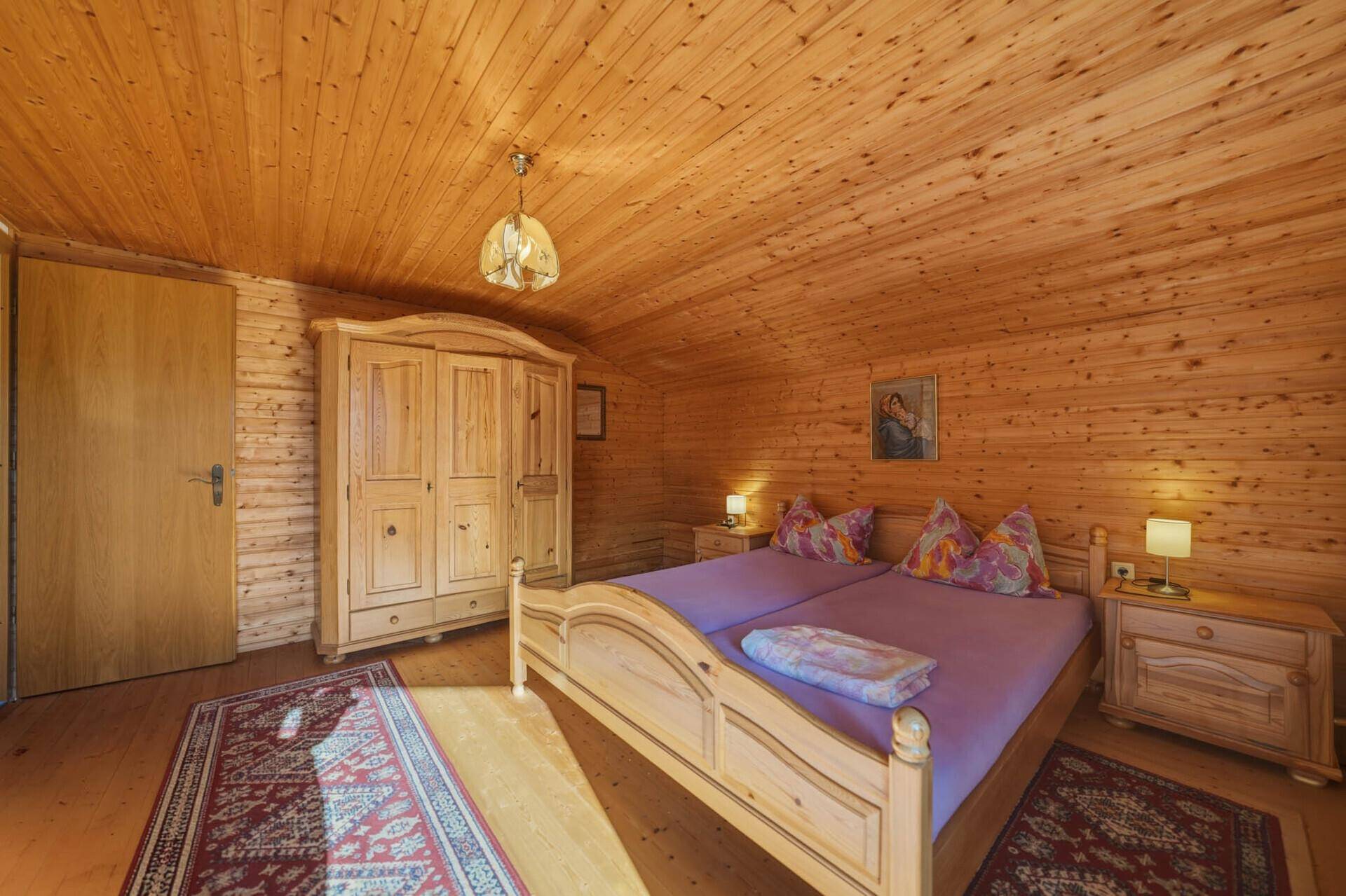 Gemütliches Schlafzimmer mit Holzverkleidung, Doppelbett und rustikalem Kleiderschrank.