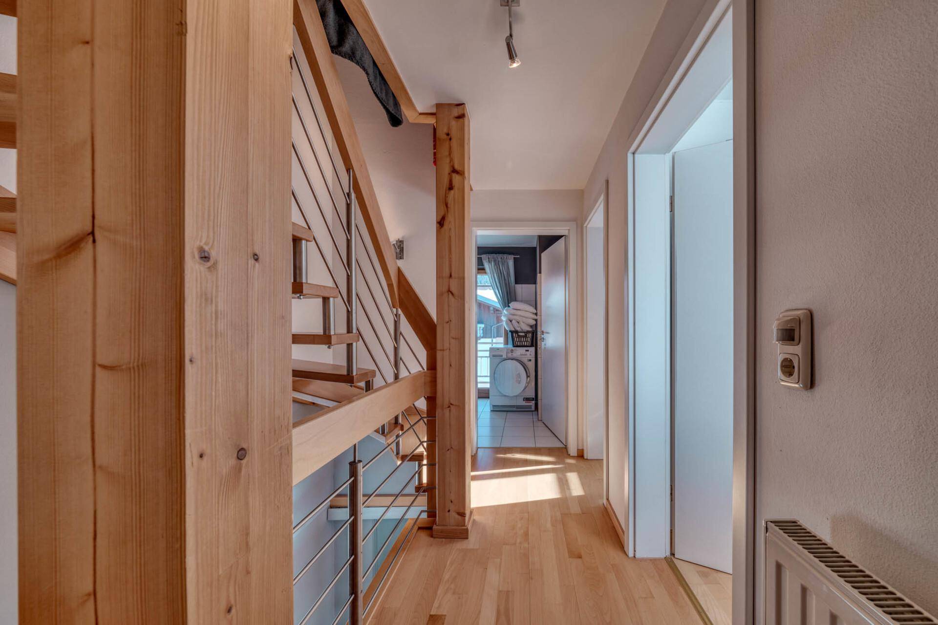 Heller Flur mit Holztreppe und Zugang zu weiteren Räumen.