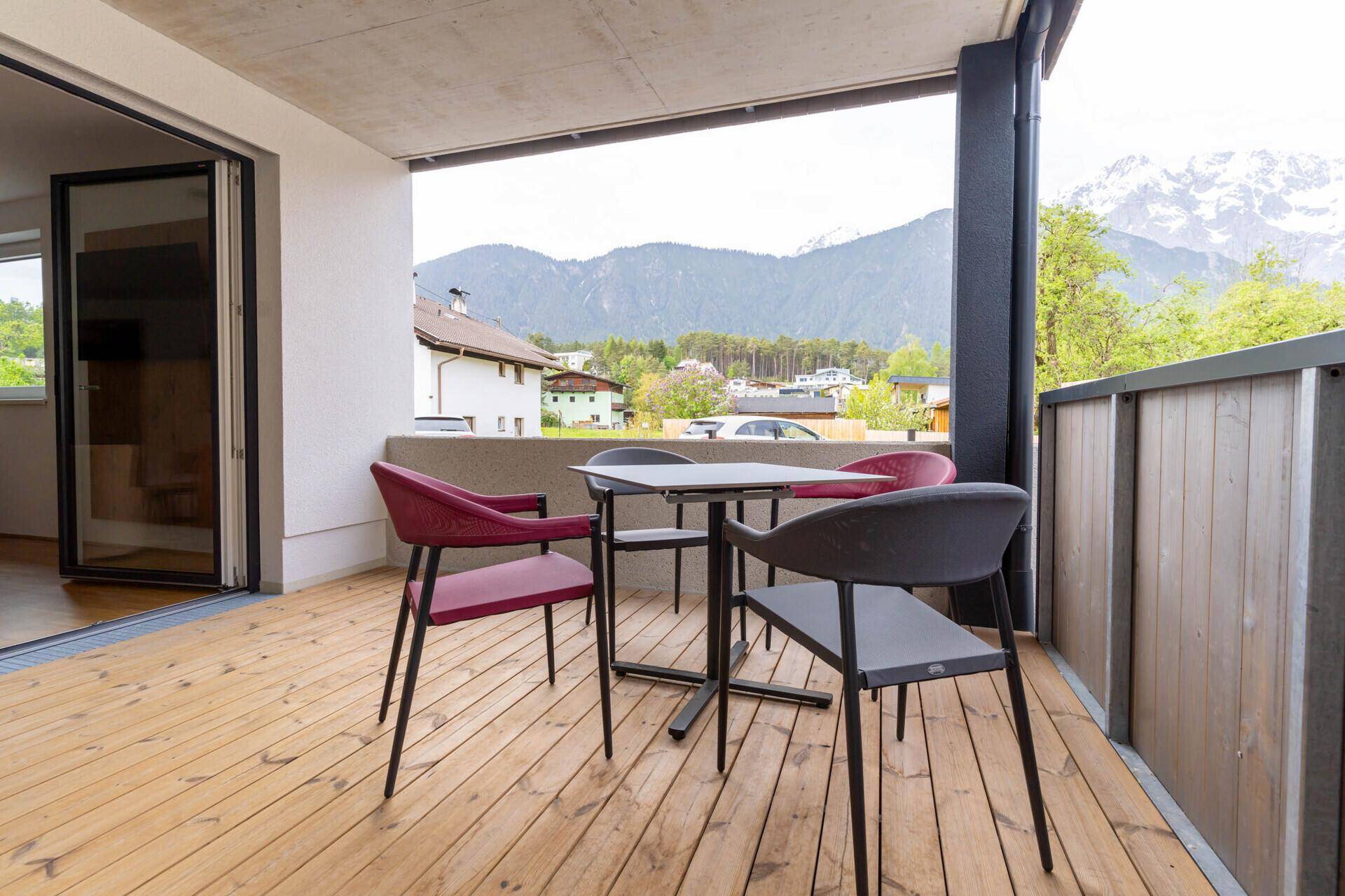 Balkon mit Holzboden, Sitzgelegenheiten und Blick auf die Berge und Umgebung.