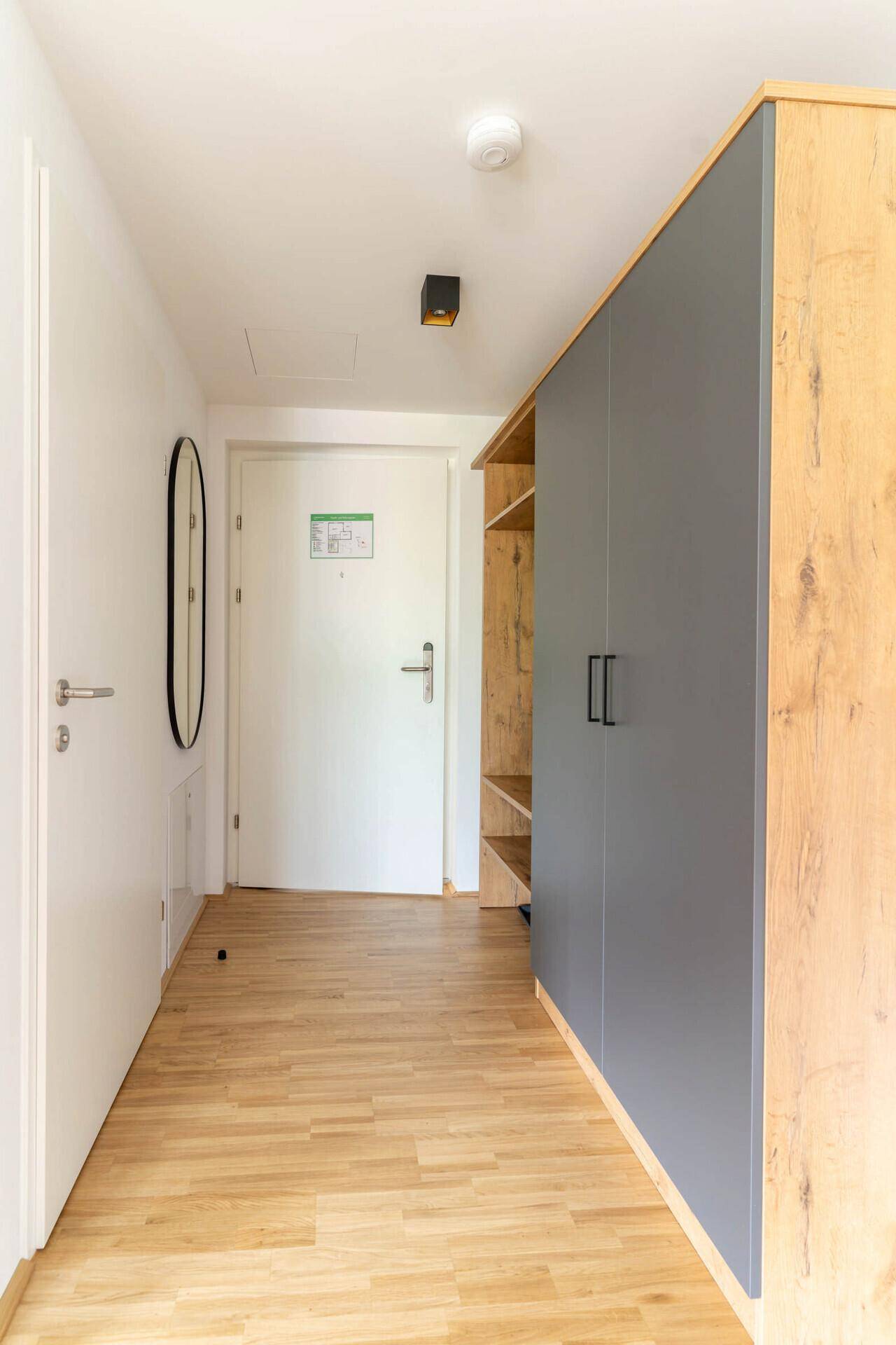 Helles Schlafzimmer mit Doppelbett, Holzboden und dekorativer Wandgestaltung.