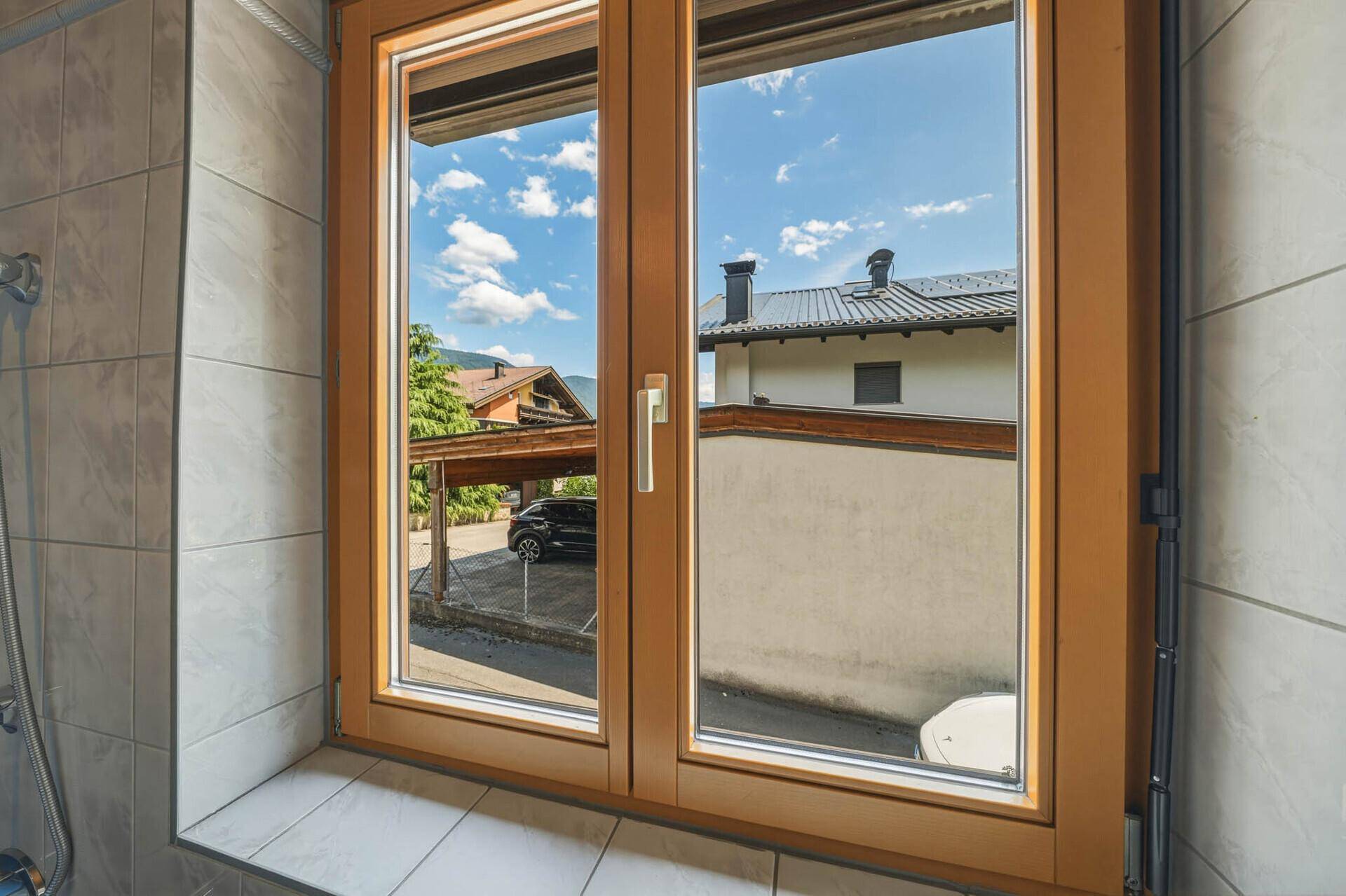 Fenster mit Blick auf die Dächer der Nachbarhäuser und den blauen Himmel mit Wolken.