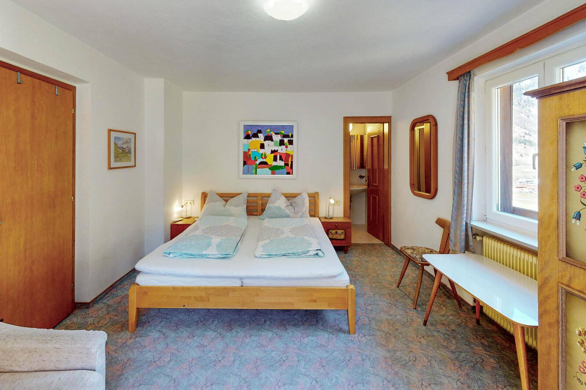 Schlafzimmer mit Doppelbett, Teppichboden und traditionellen Möbeln.