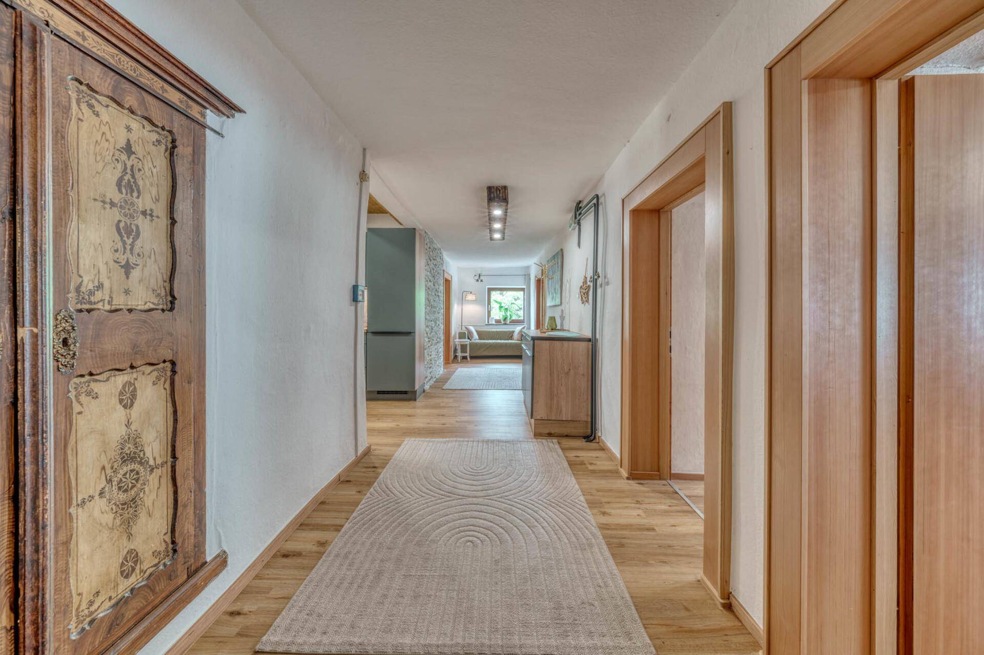 Heller Flur mit Holzboden und traditionellem Schrank, der zu weiteren Räumen führt.