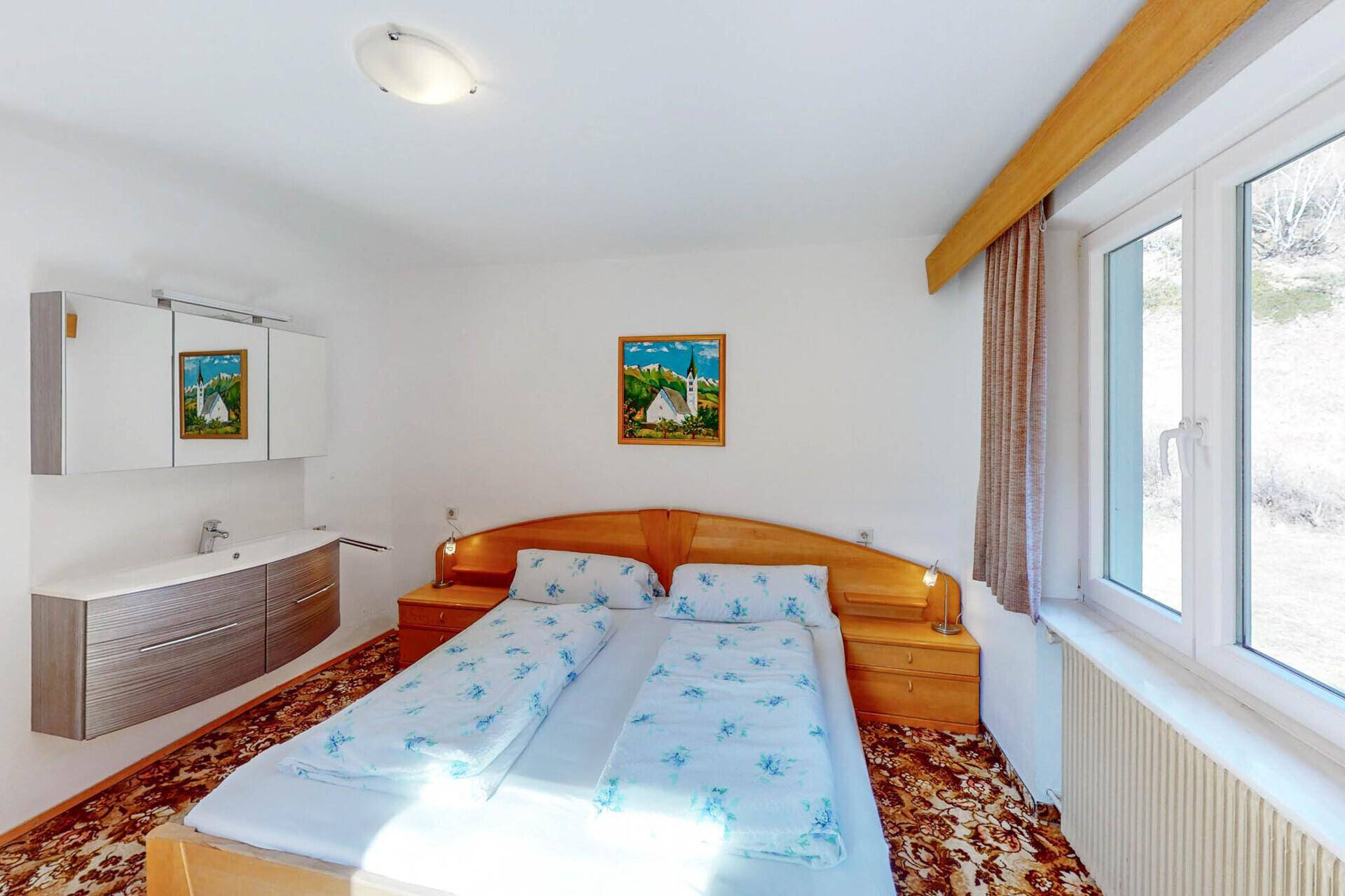 Schlafzimmer mit Doppelbett, Teppichboden und integriertem Waschbecken.
